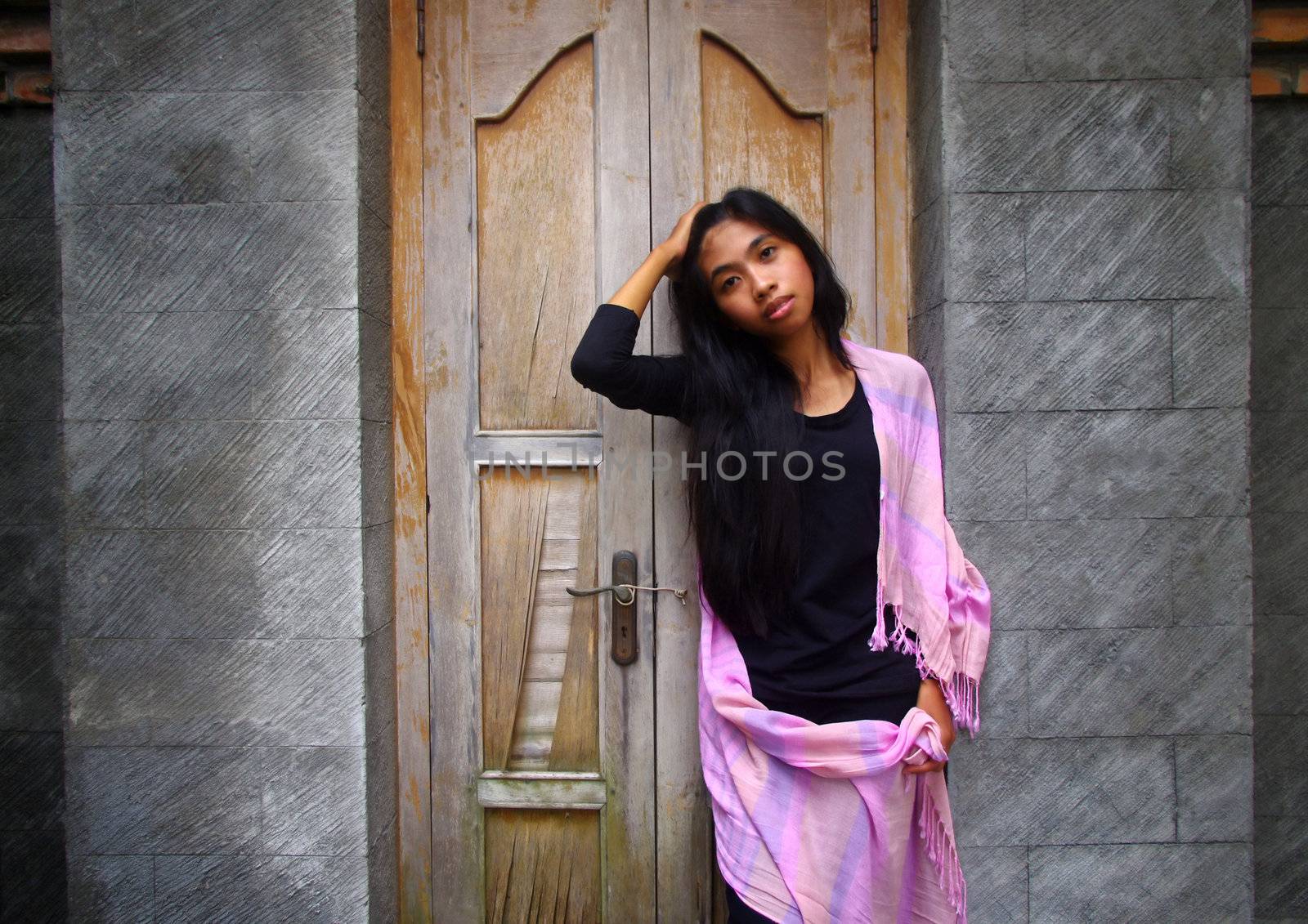 Young Asian woman standing infront of wooden door.