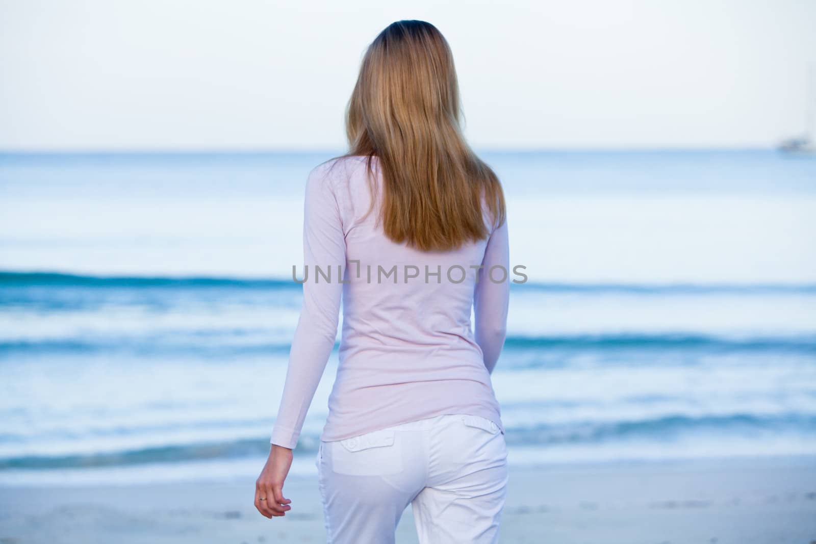 attractive young blonde woman walking on the beach in summer vacation 