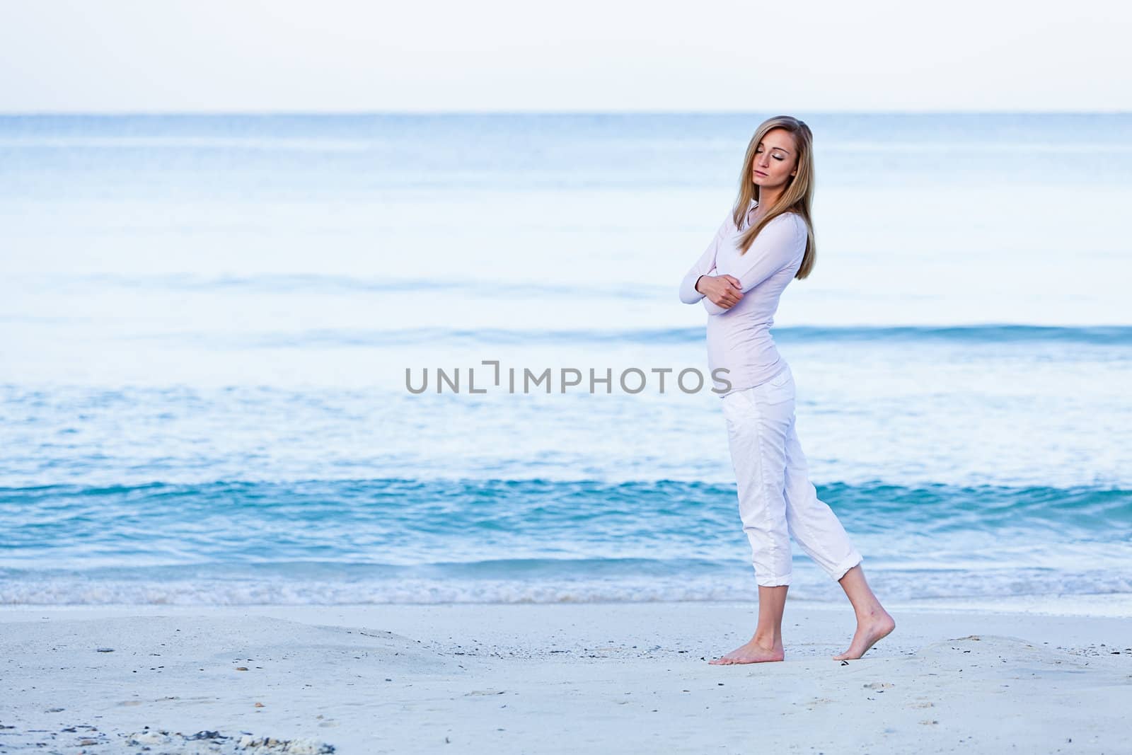 attractive young blonde woman walking on the beach in summer vacation 