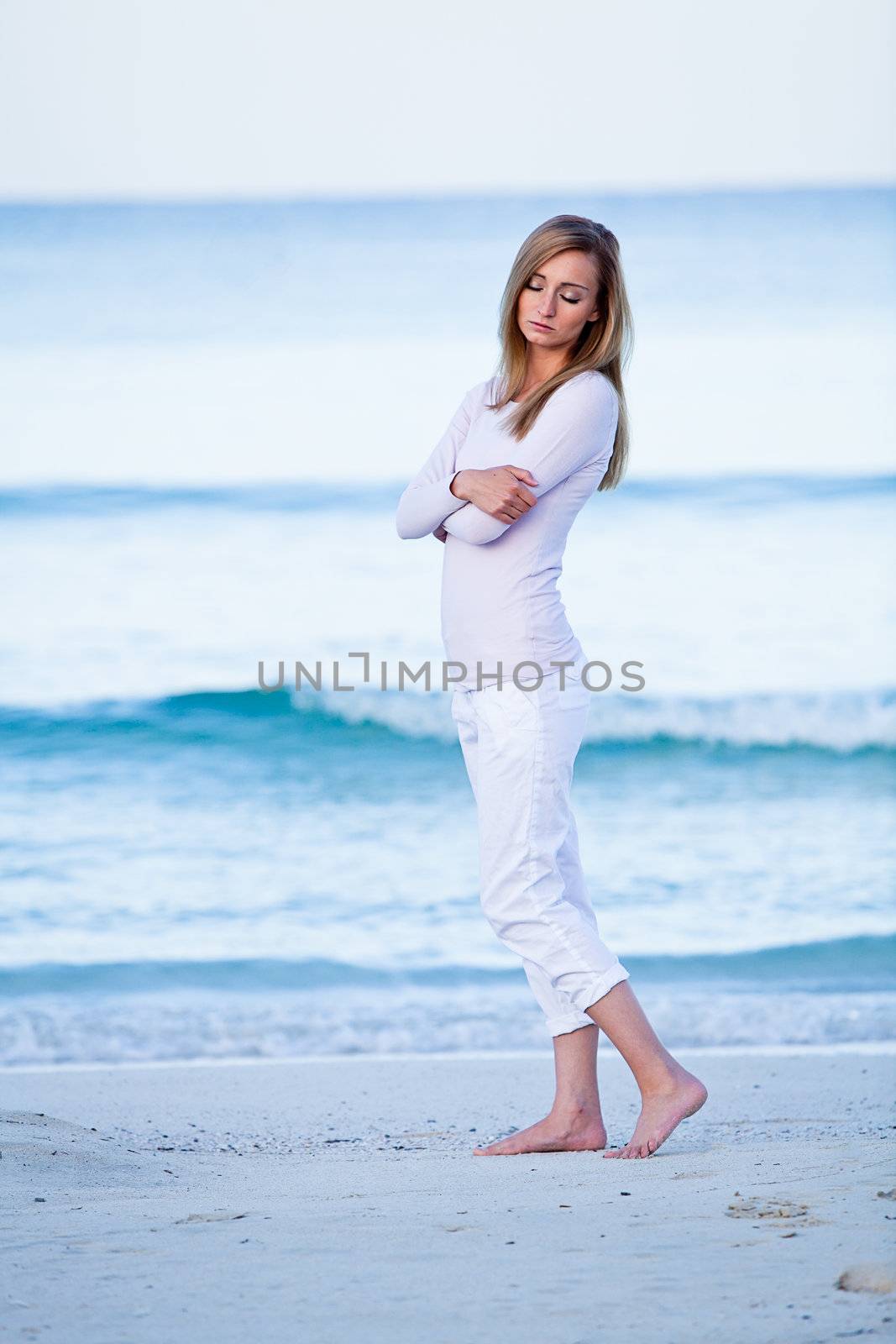 attractive young blonde woman walking on the beach in summer vacation 