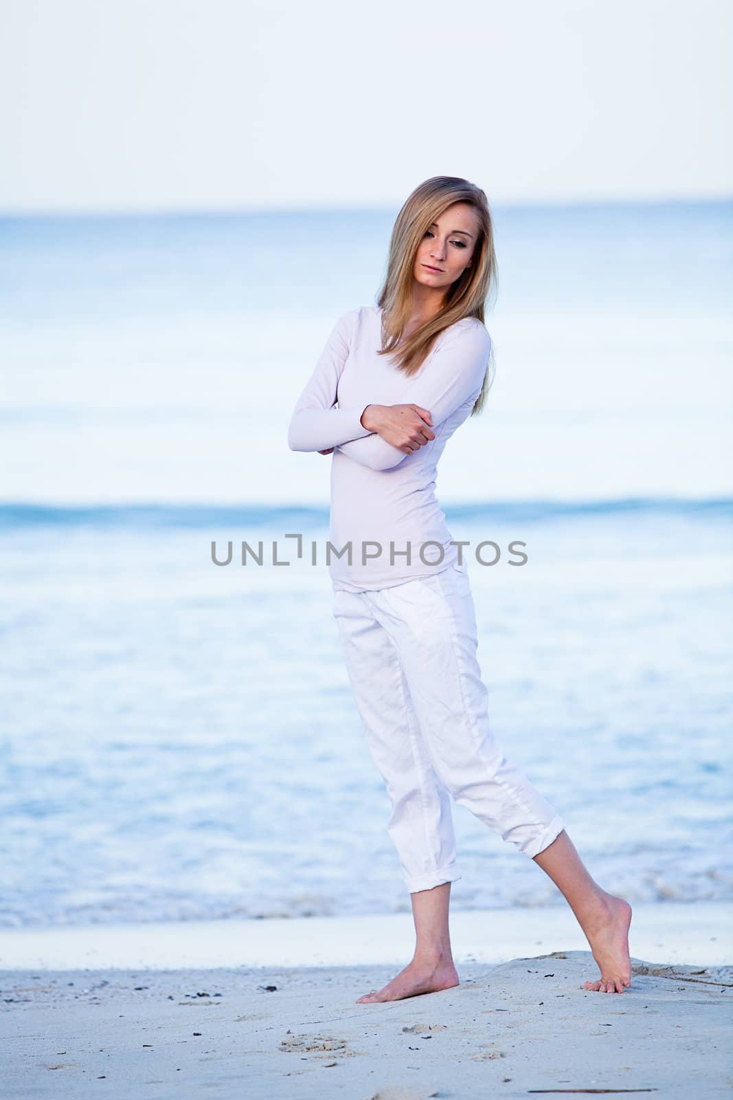 attractive young blonde woman walking on the beach in summer vacation 