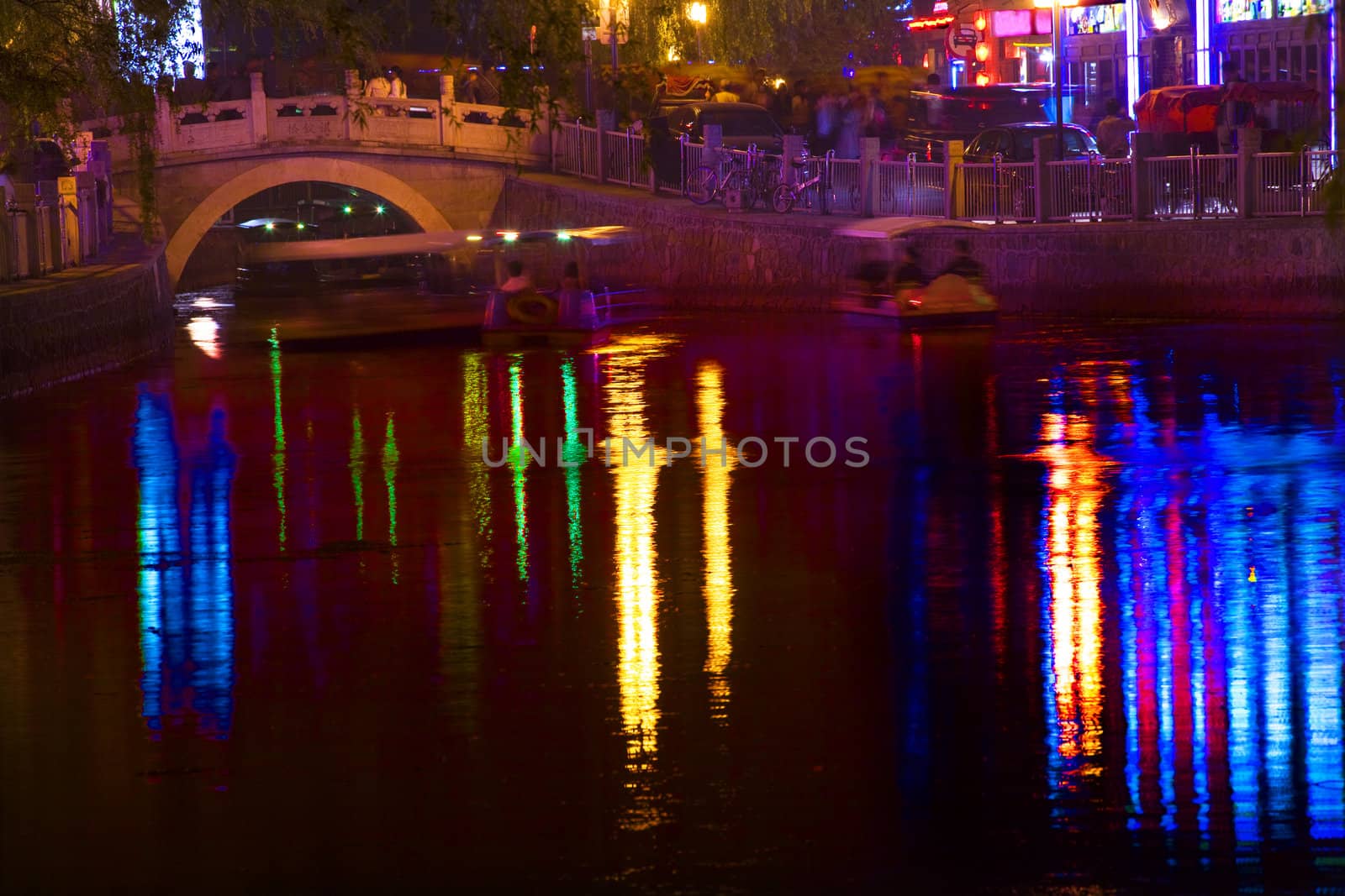 Houhai Lake Bar District Silver Ingot Bridge Red Blue Lights at Night with Reflections Beijing China Trademarks removed.




