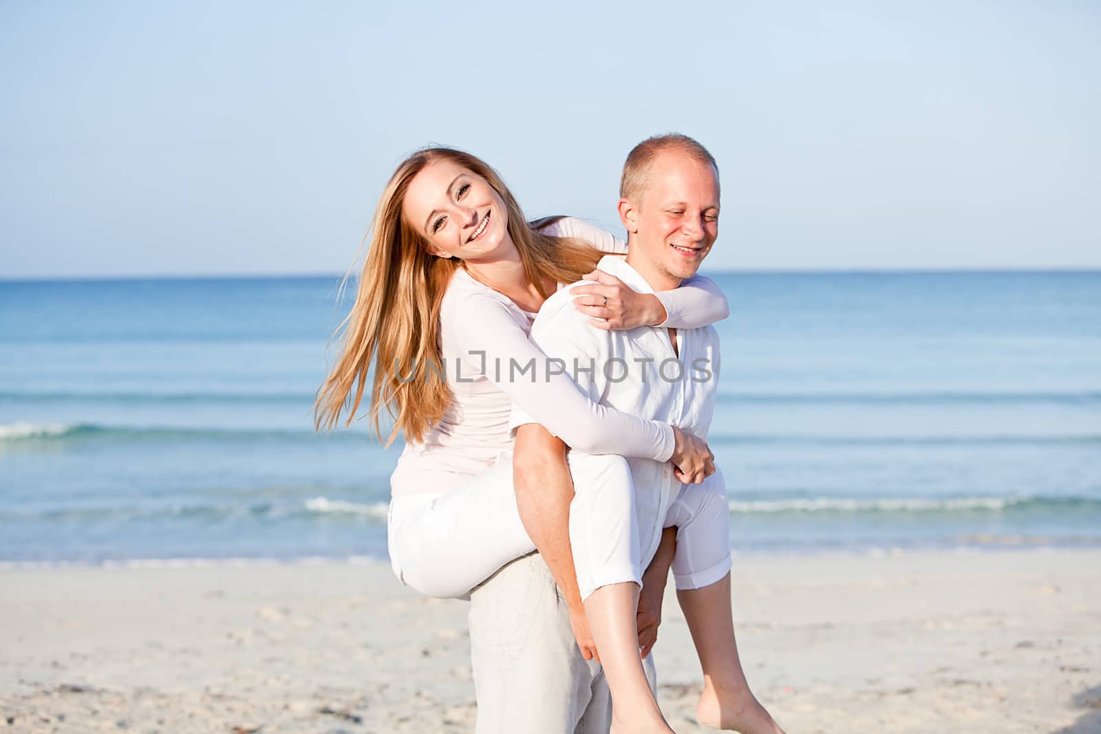 happy young couple in love having fun on the beach blue sky and sunshine 