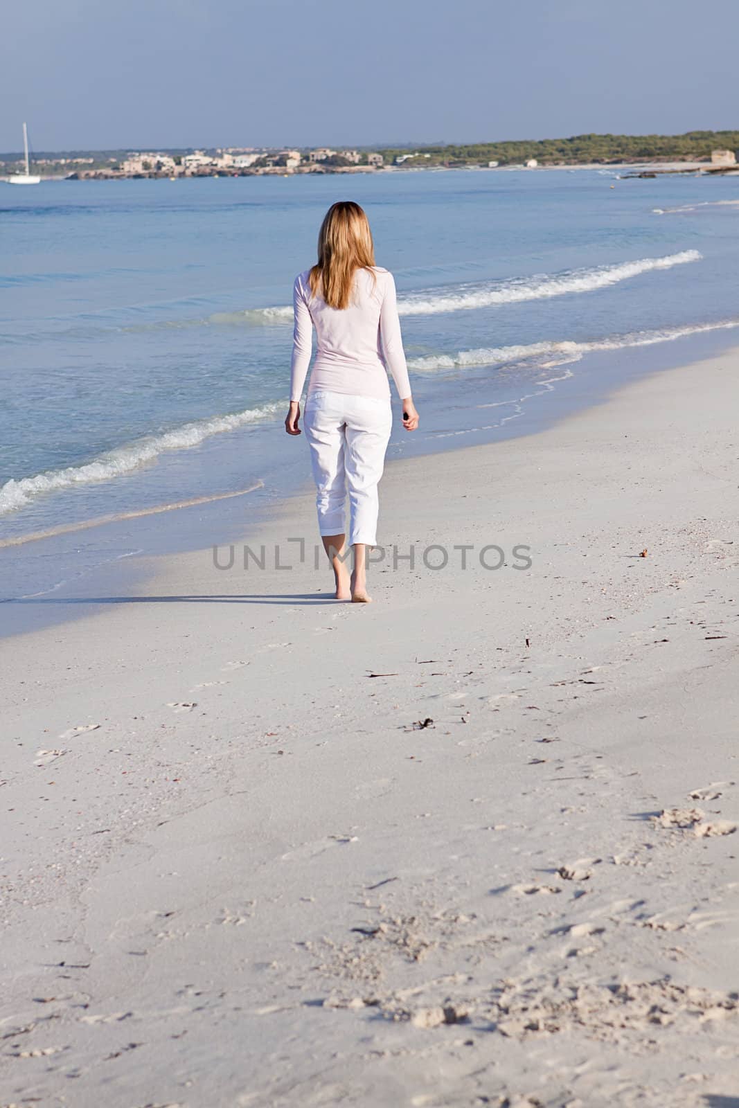 attractive young blonde woman walking on the beach in summer vacation 