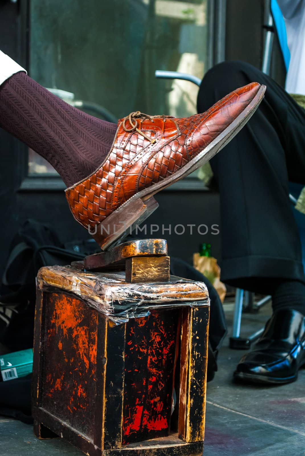 Photograph of a Shoeshiners own shoe on his shining stand waiting for customers.