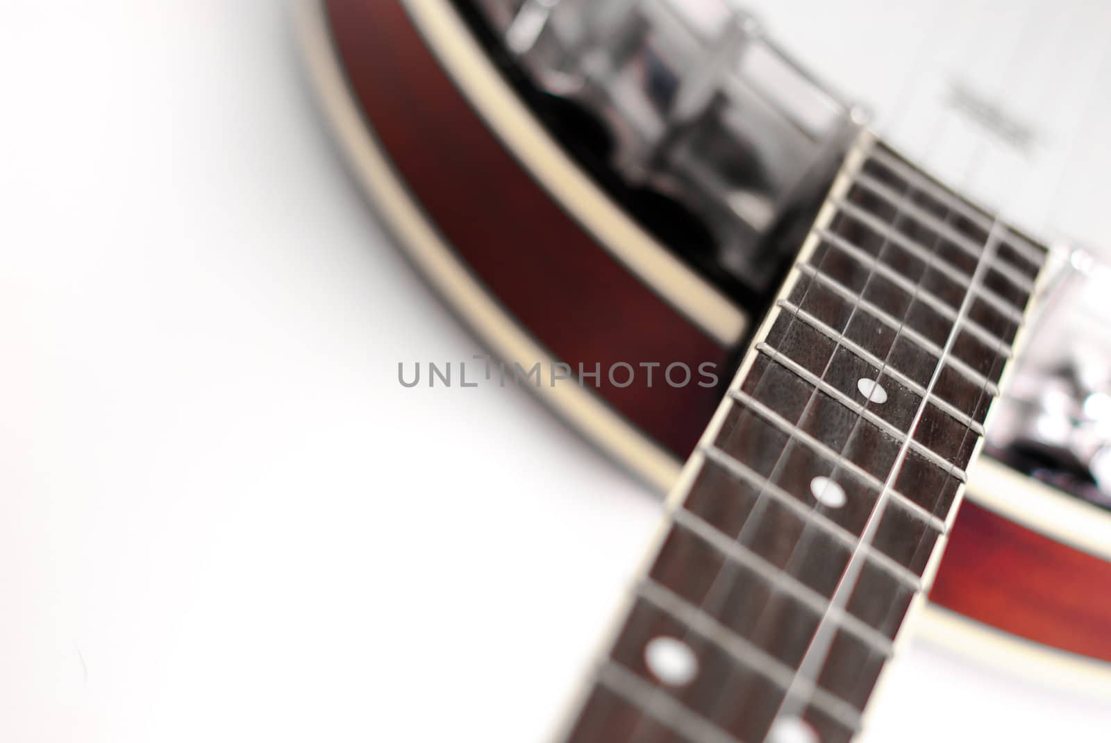 Photogrpah of a Banjo on white background with selective focus on the high frets.