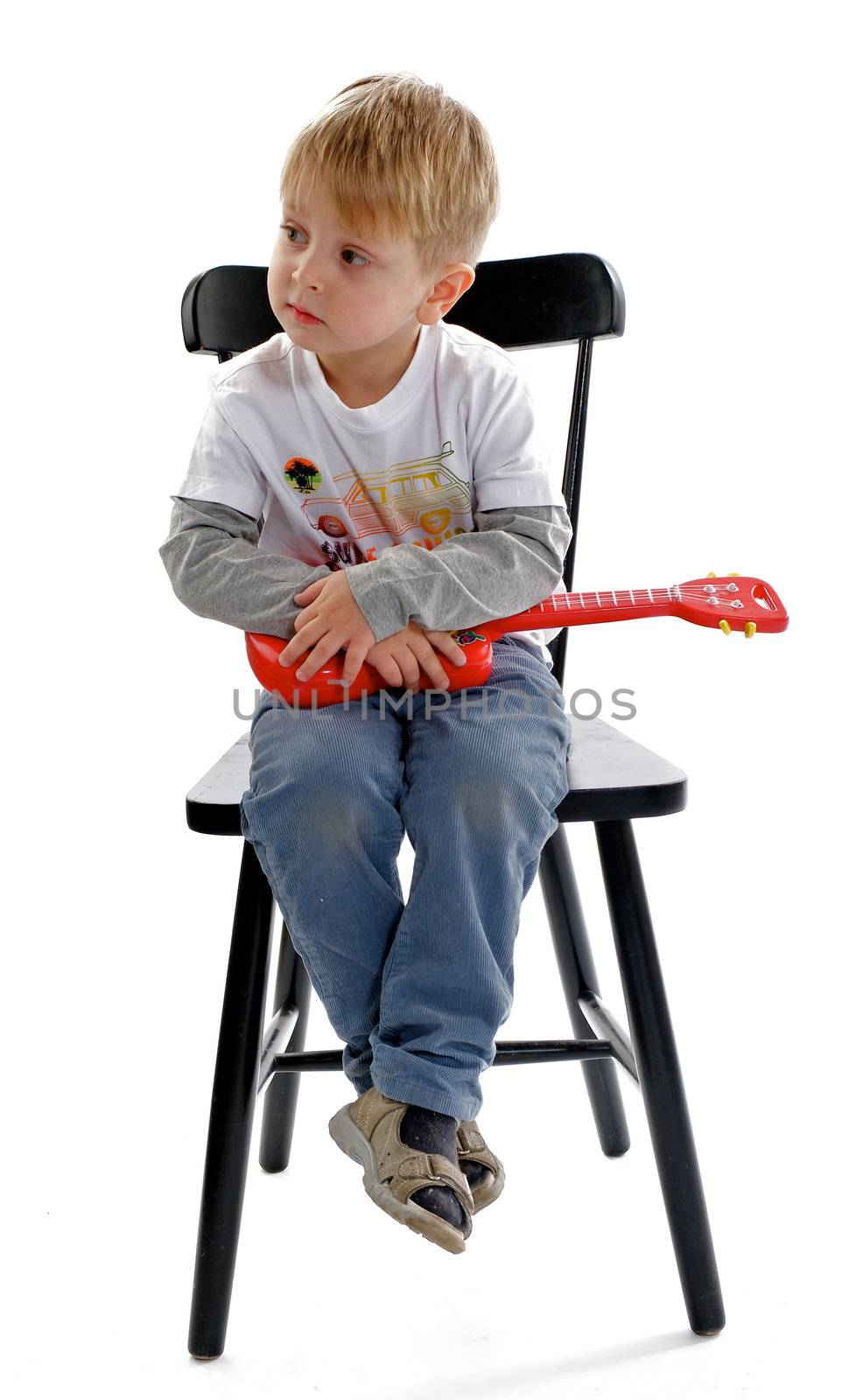 Little Boy Sitting on Chair and Holding his Toy Guitar 