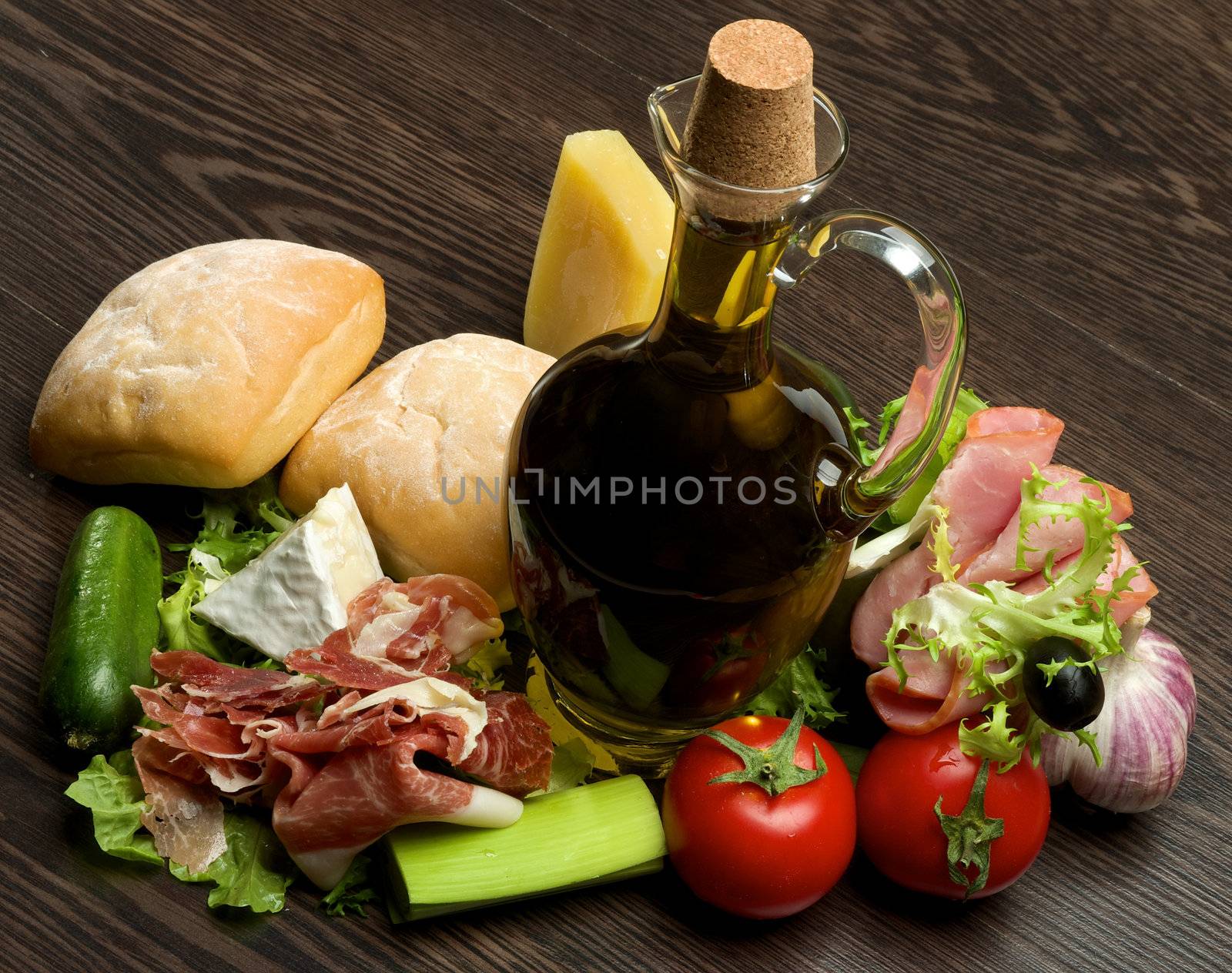 Provençal Still Life with Vegetables, Hamon, Ciabatta, Cheese and Olive Oil closeup on Dark Wood background