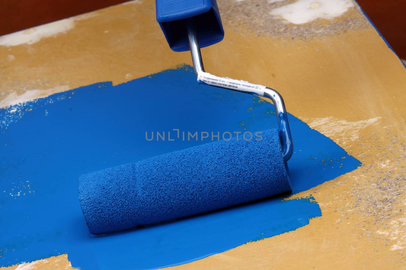 Roller brush with blue paint close up 