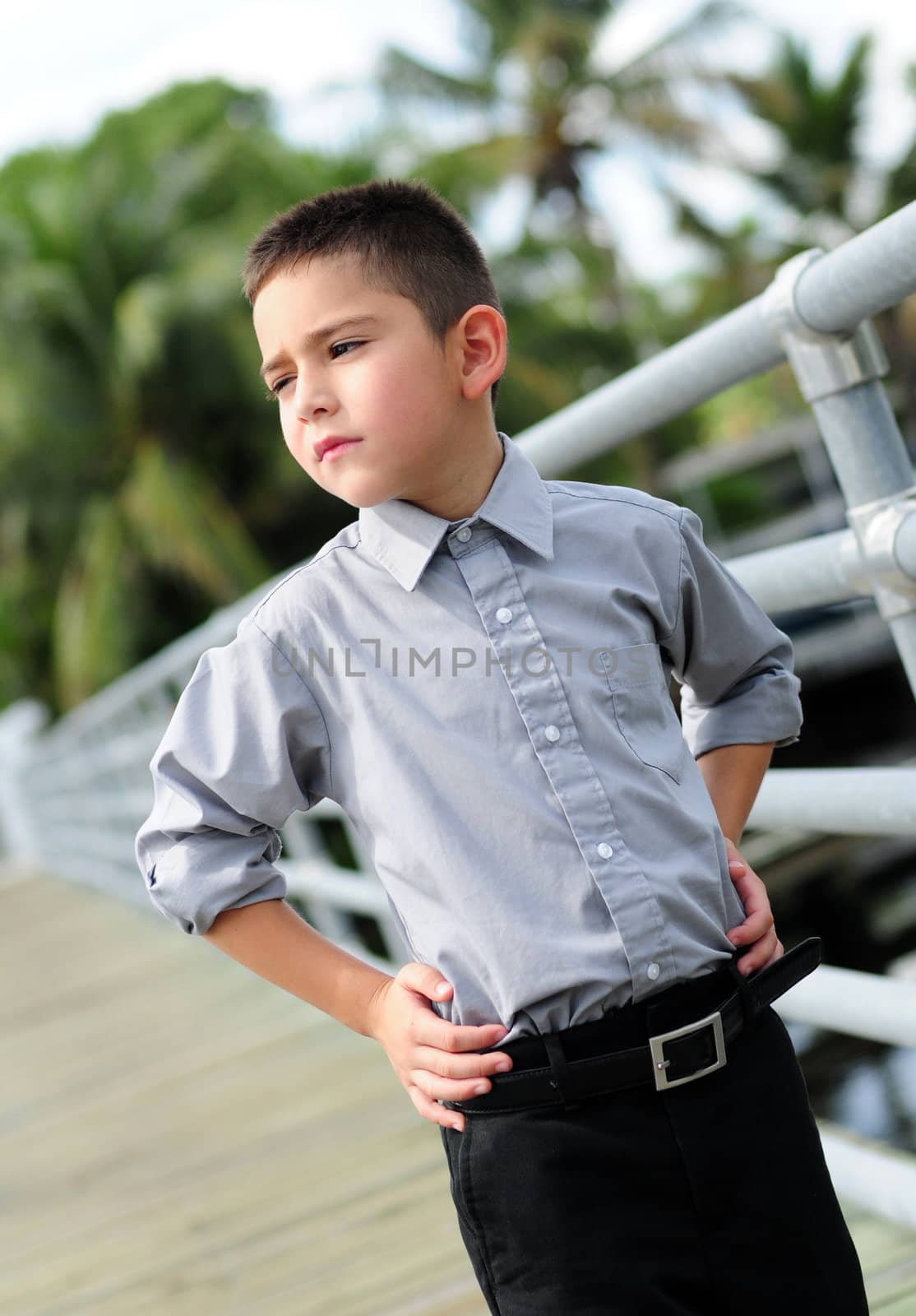 Serious young boy outdoors with hands on hips