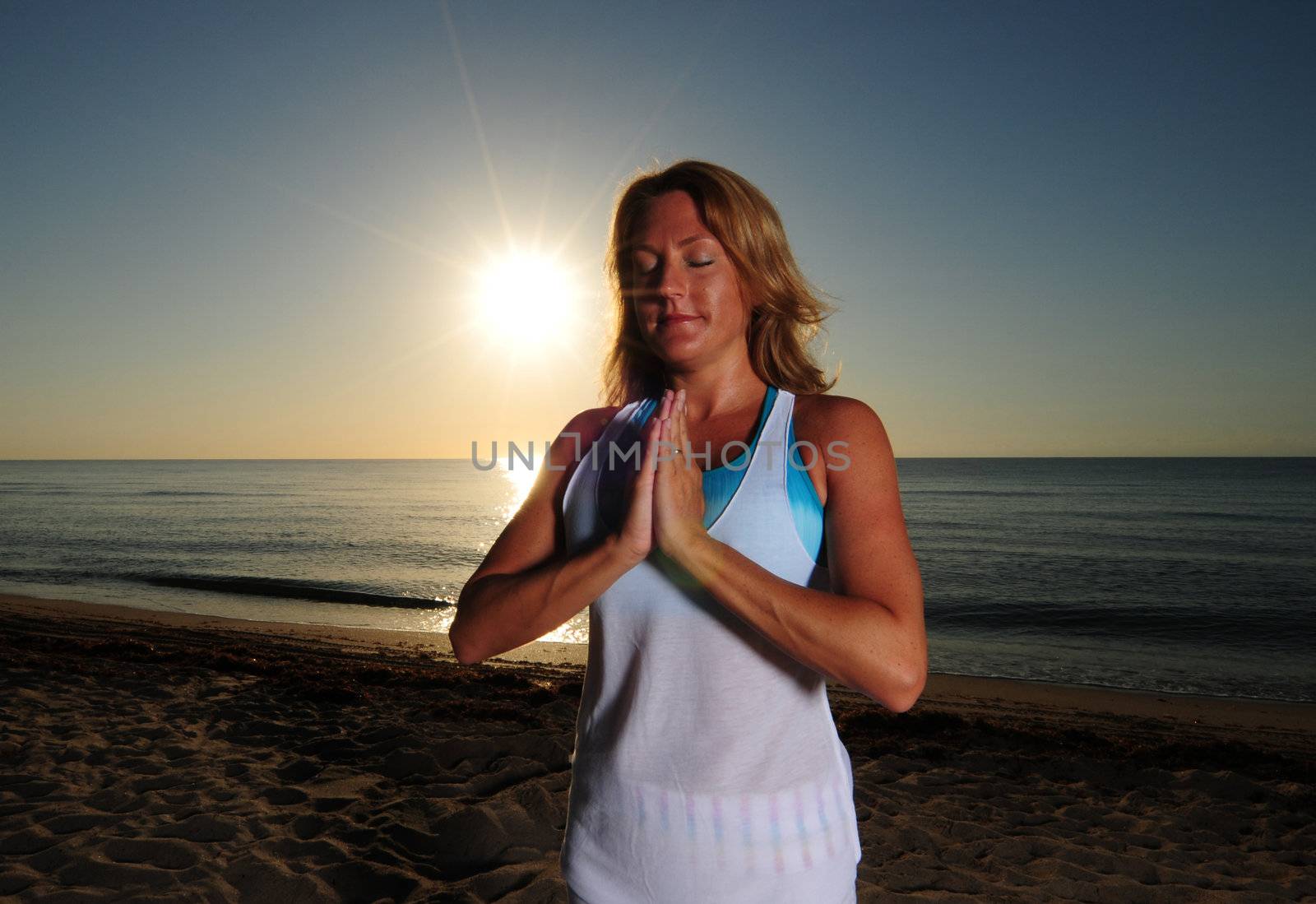 Woman meditating during sunrise on a beach