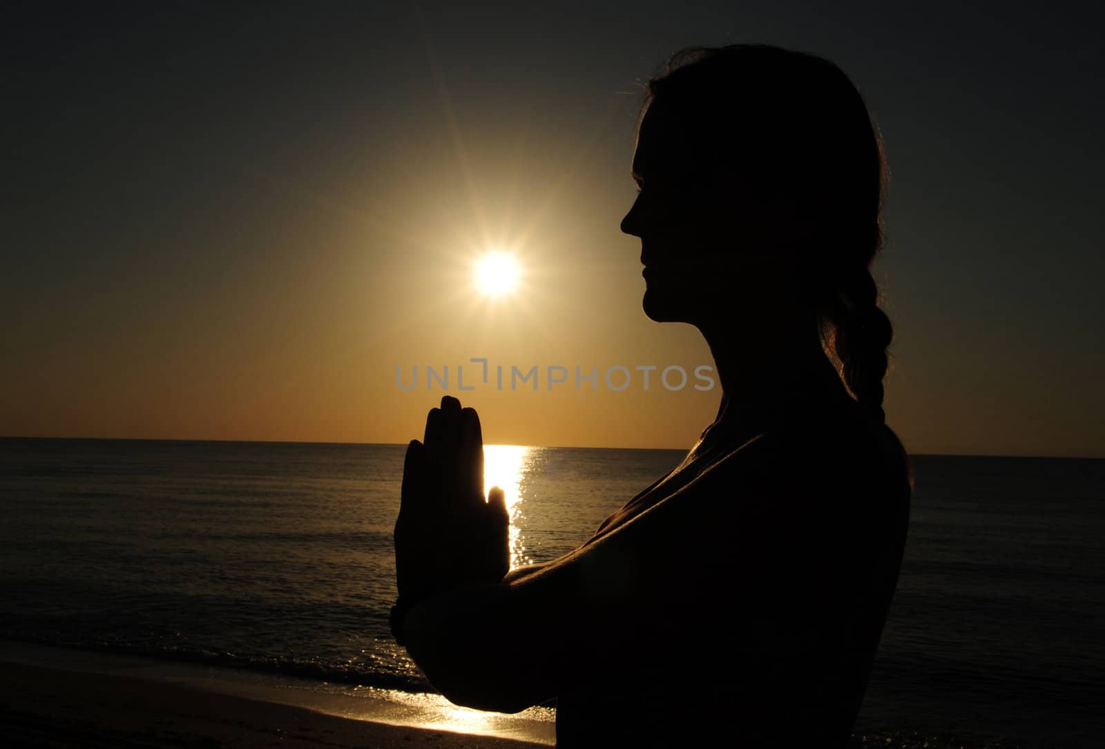 woman praying or meditating during sunrise on the beach