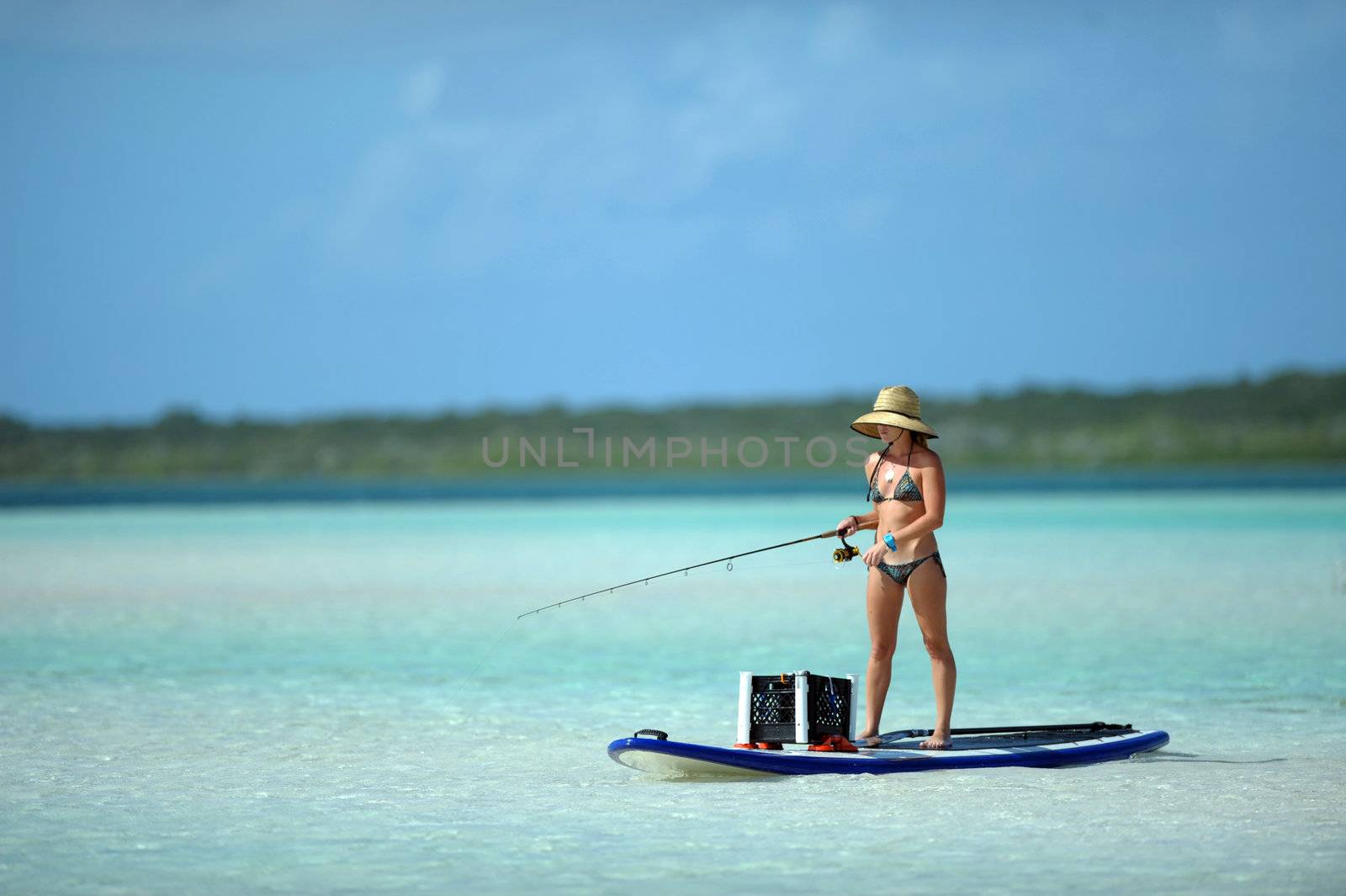 Beautiful woman in bikini fishing and paddleboarding in the bahamas