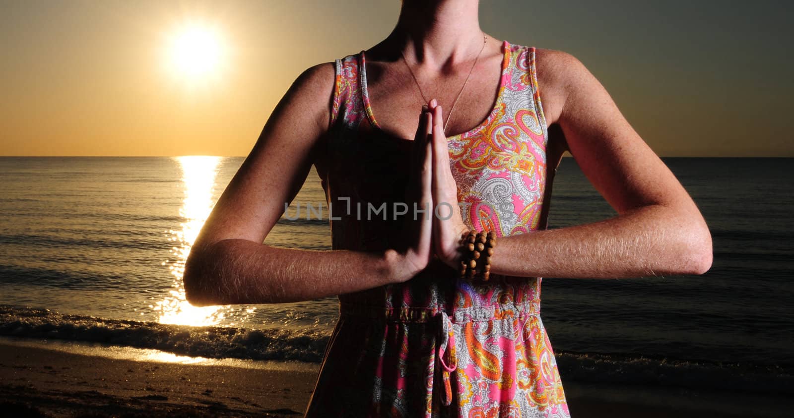 Woman Woman meditating or praying on beach with sunrise