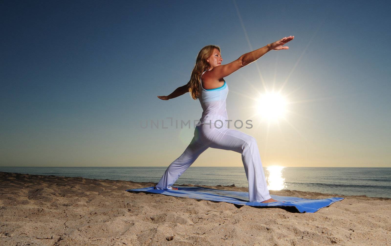 Woman doing Warrior Pose II (Virabhadrasana II) yoga pose on beach