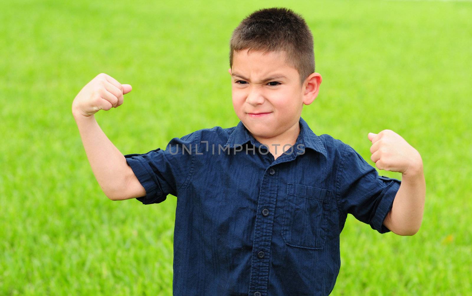 Young boy who is flexing his muscles with a mean face