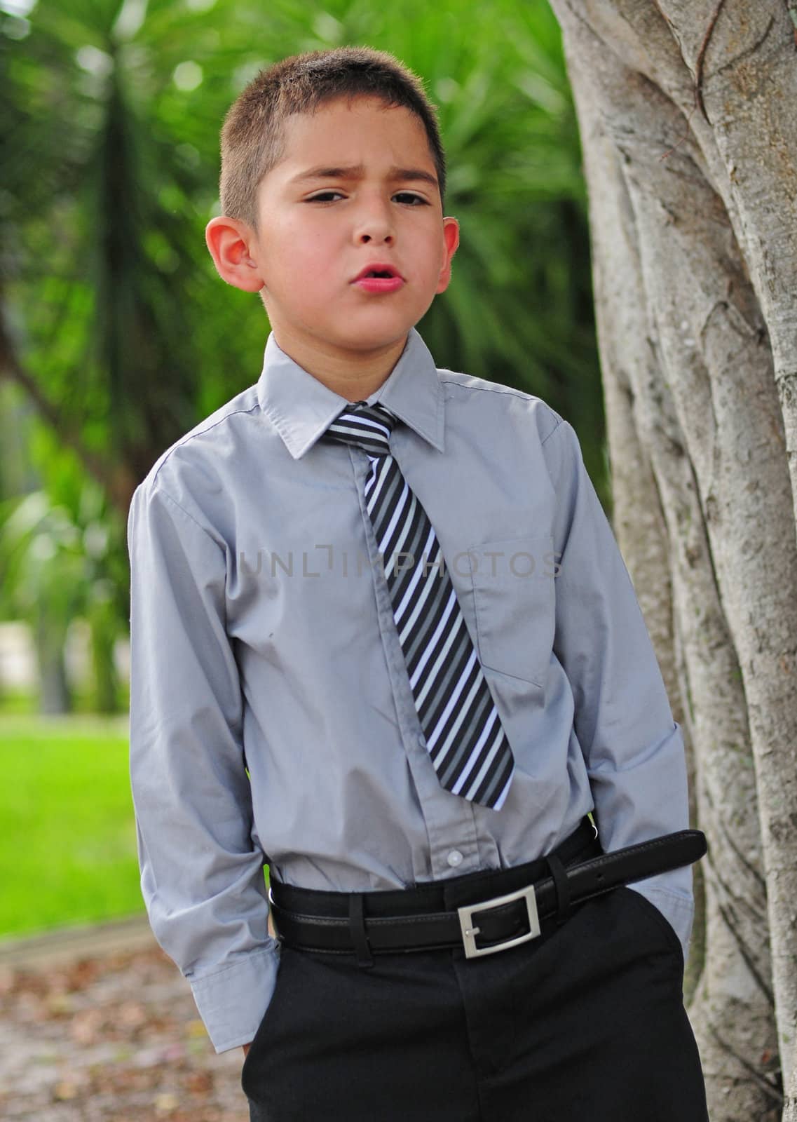 Serious attractive young boy in business attire with serious face and hands in pocket