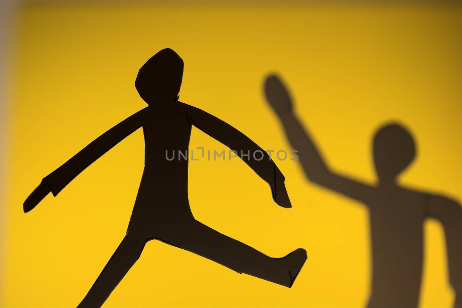 people silhouette cut in small rudimentary figures  in paper , shot with colorfull background