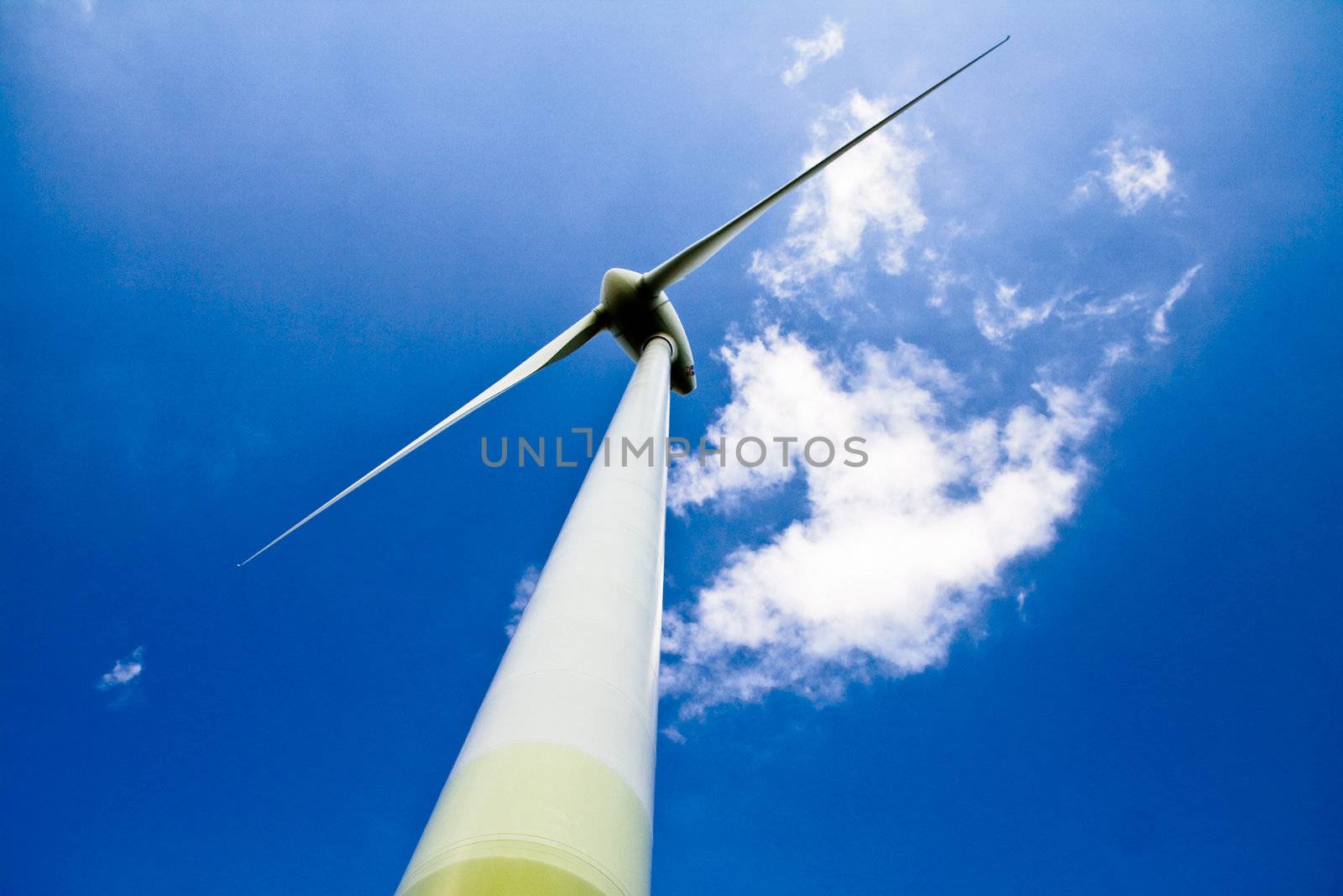 Windmill against a blue sky and clouds, alternative energy source, in horizontal frame