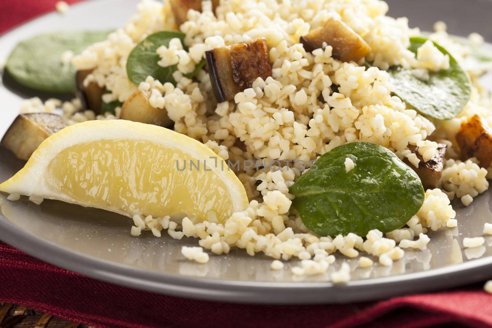 Bulgur salad with spinach roasted eggplant and a lemon wedge