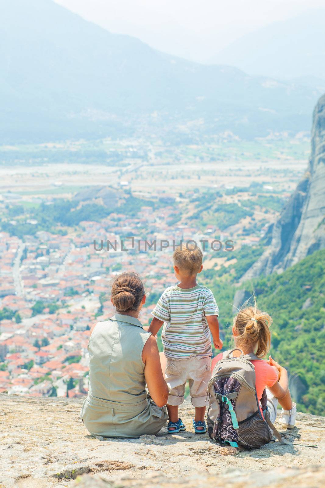 Mother and her kids looking at the town of Kalambaka bird's eye view. Vertical view. Meteora, Greece.