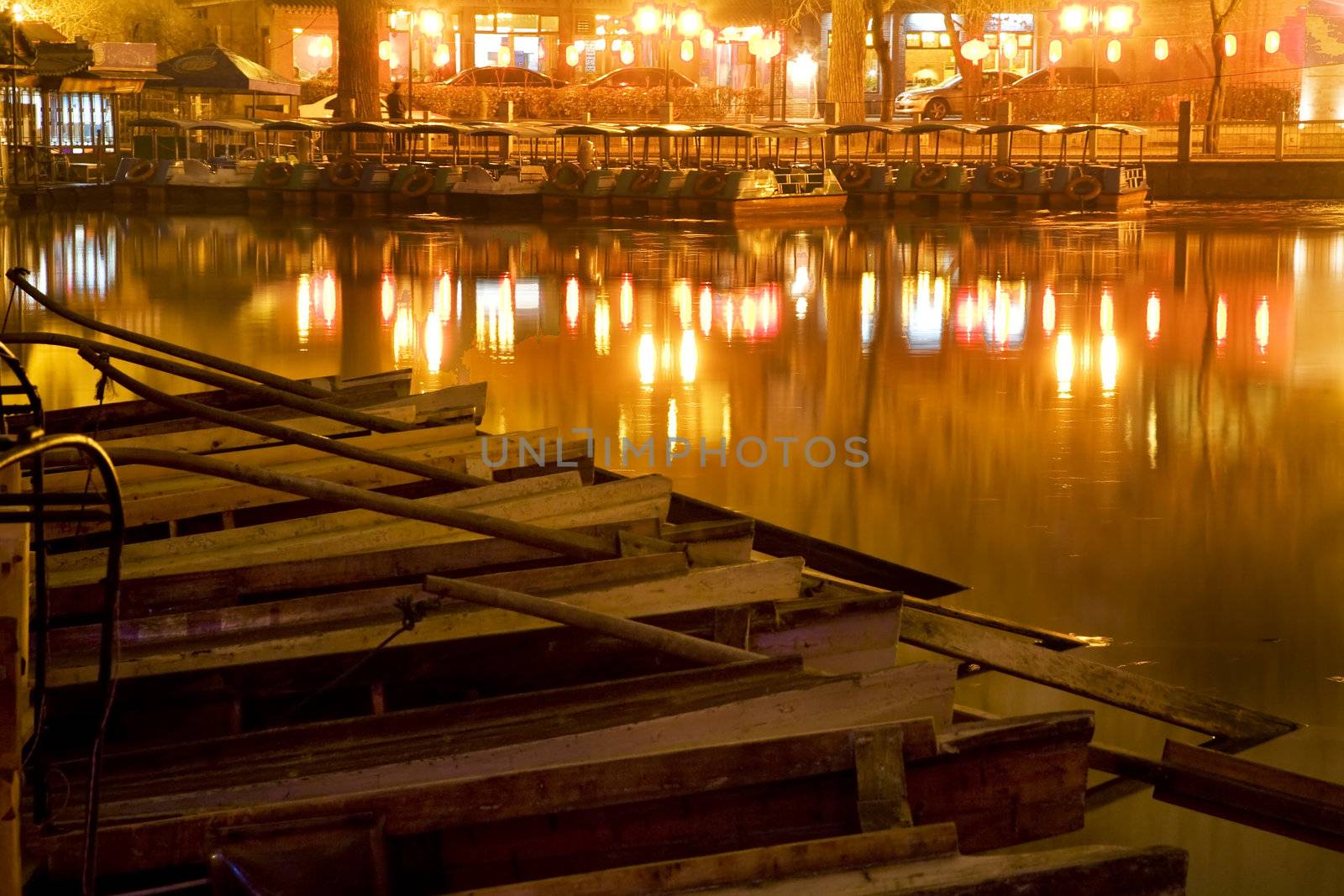 Wooden Boats on Houhai Lake with Lights of Bars and Restaurants in background, Beijing, China.  Hohai is the old swimming hole in the City and is now surrounded by bars and restaurants and is one of the well-known night districts in Beijing.