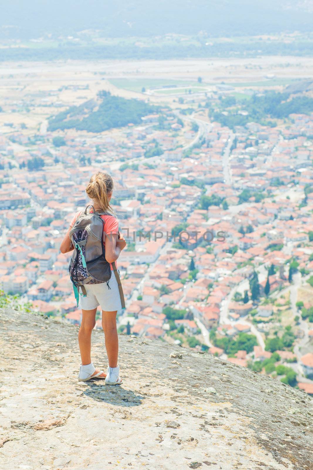 Girl looking at the town of Kalambaka bird's eye view. Meteora, Greece. Vertical view