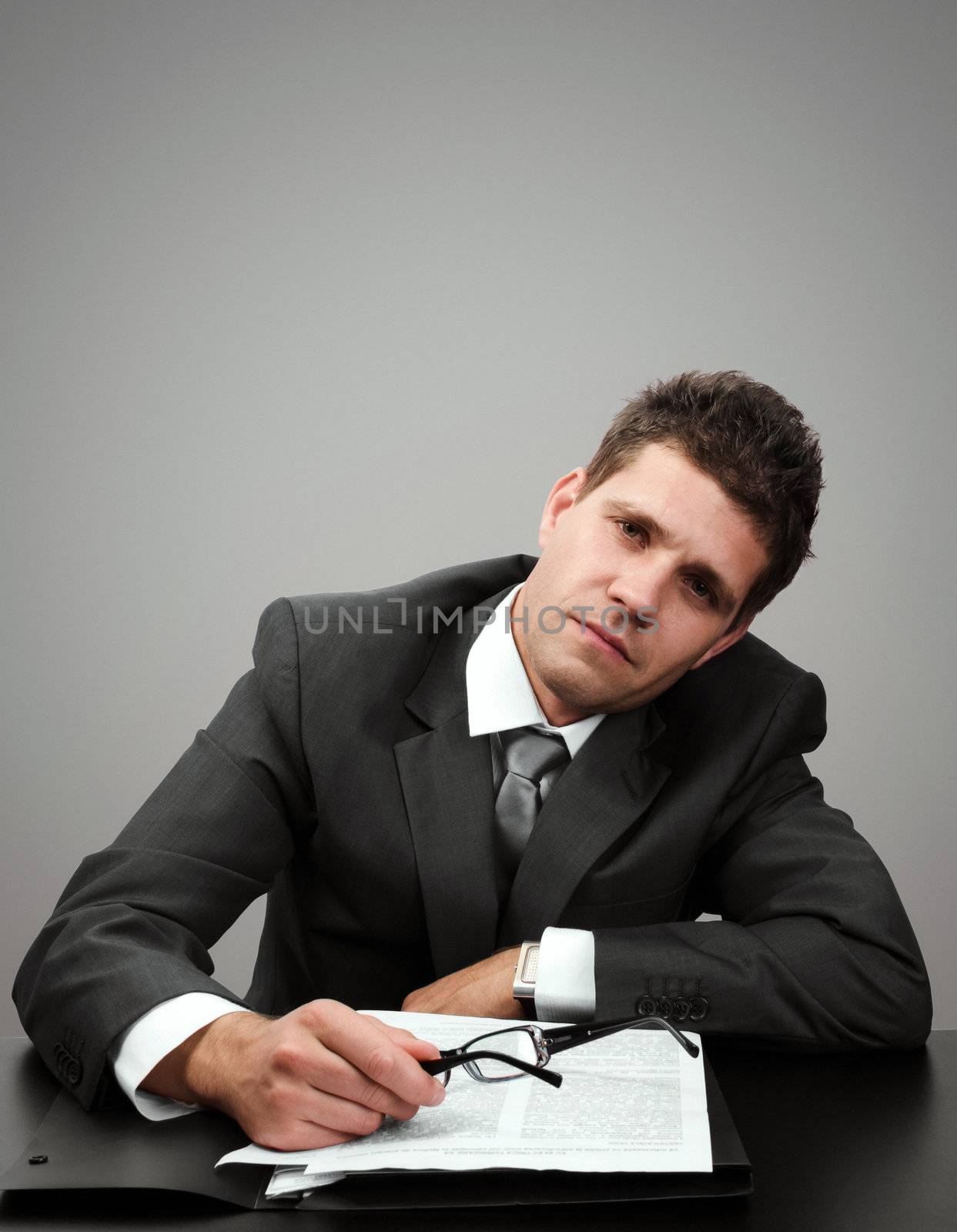 Young businessman tired of paperwork looking at camera