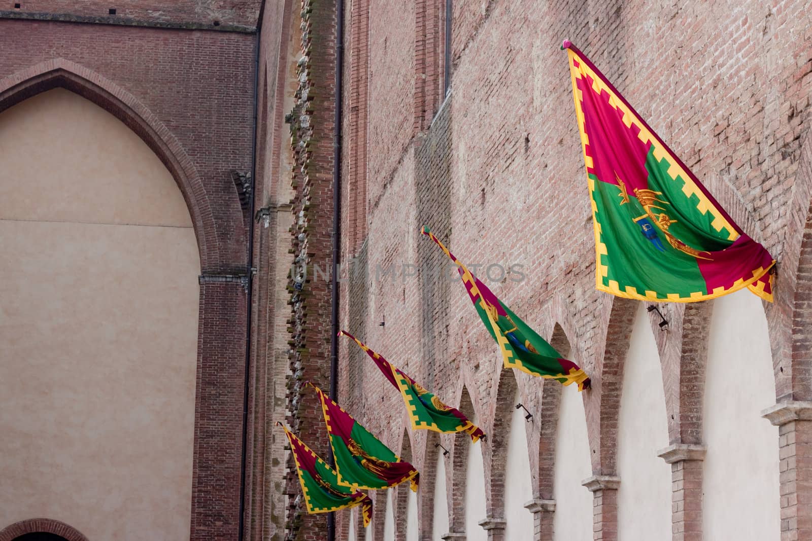 Several Siena palio banners on a wall
