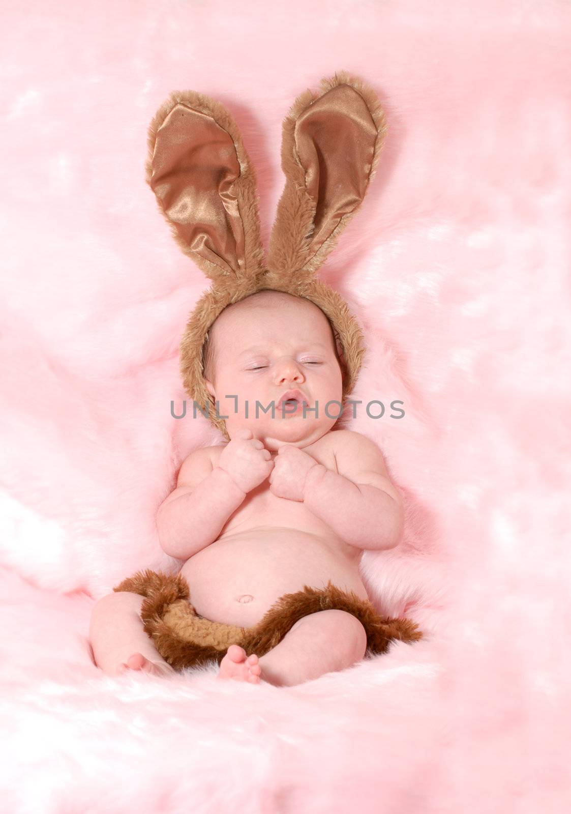 baby girl dressed up like easter bunny on pink background 