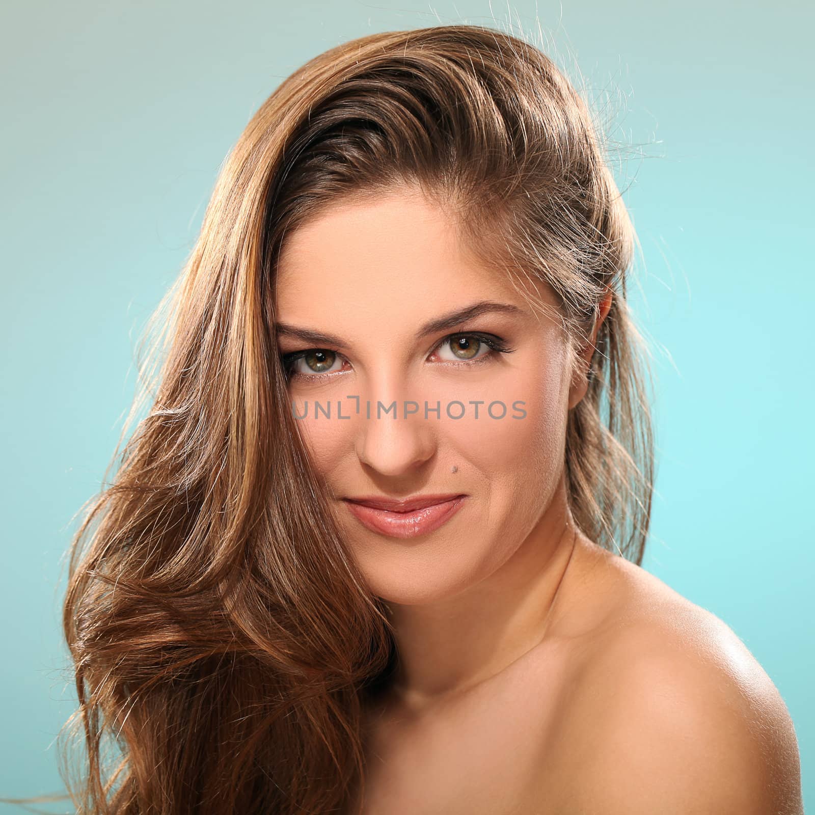 Portrait of young beautiful woman with long hair isolated over blue background