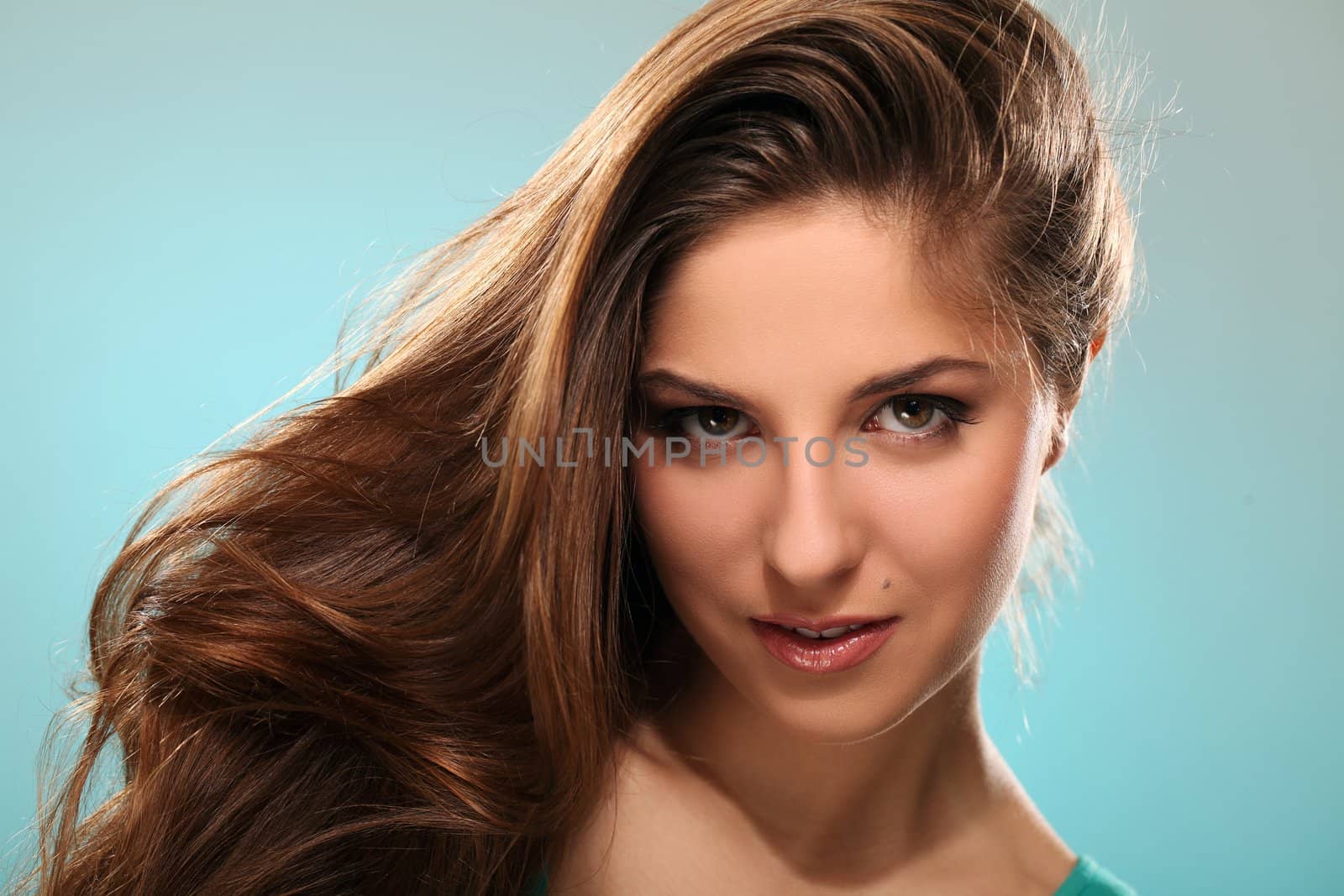 Portrait of young beautiful woman with long hair isolated over blue background