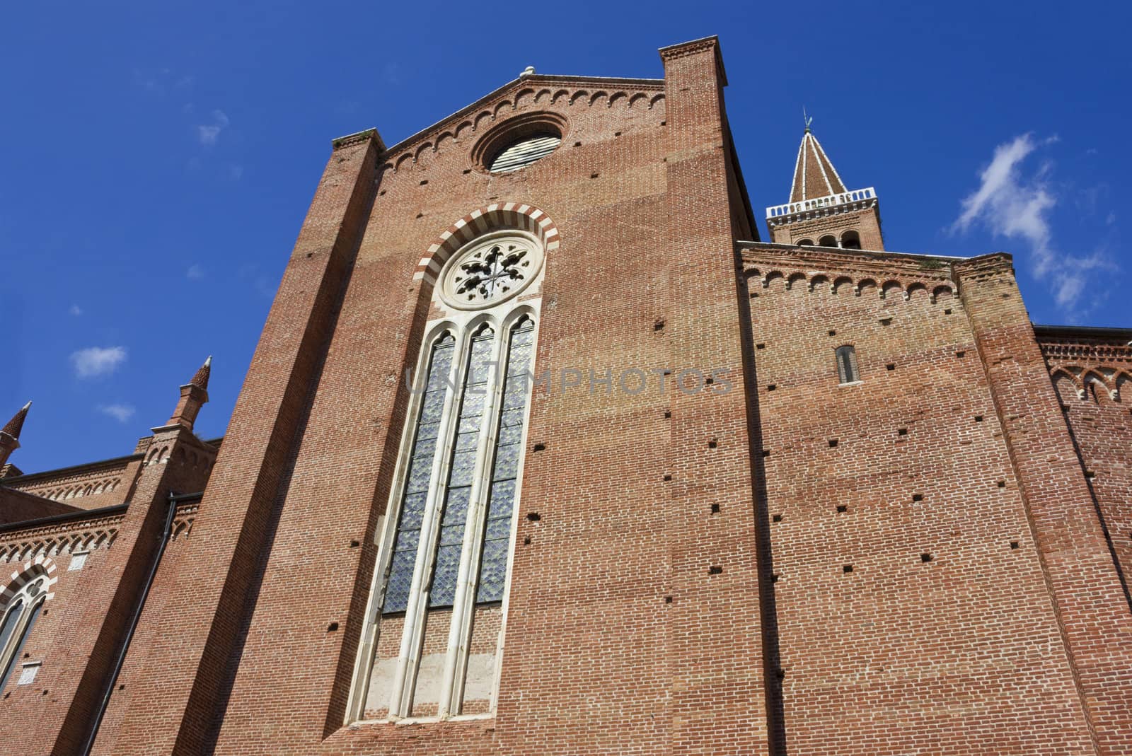 Red brick facade of the Dominican church of Sant'Anastasia in Verona, Italy in a bright sunny day, over a blue sky.