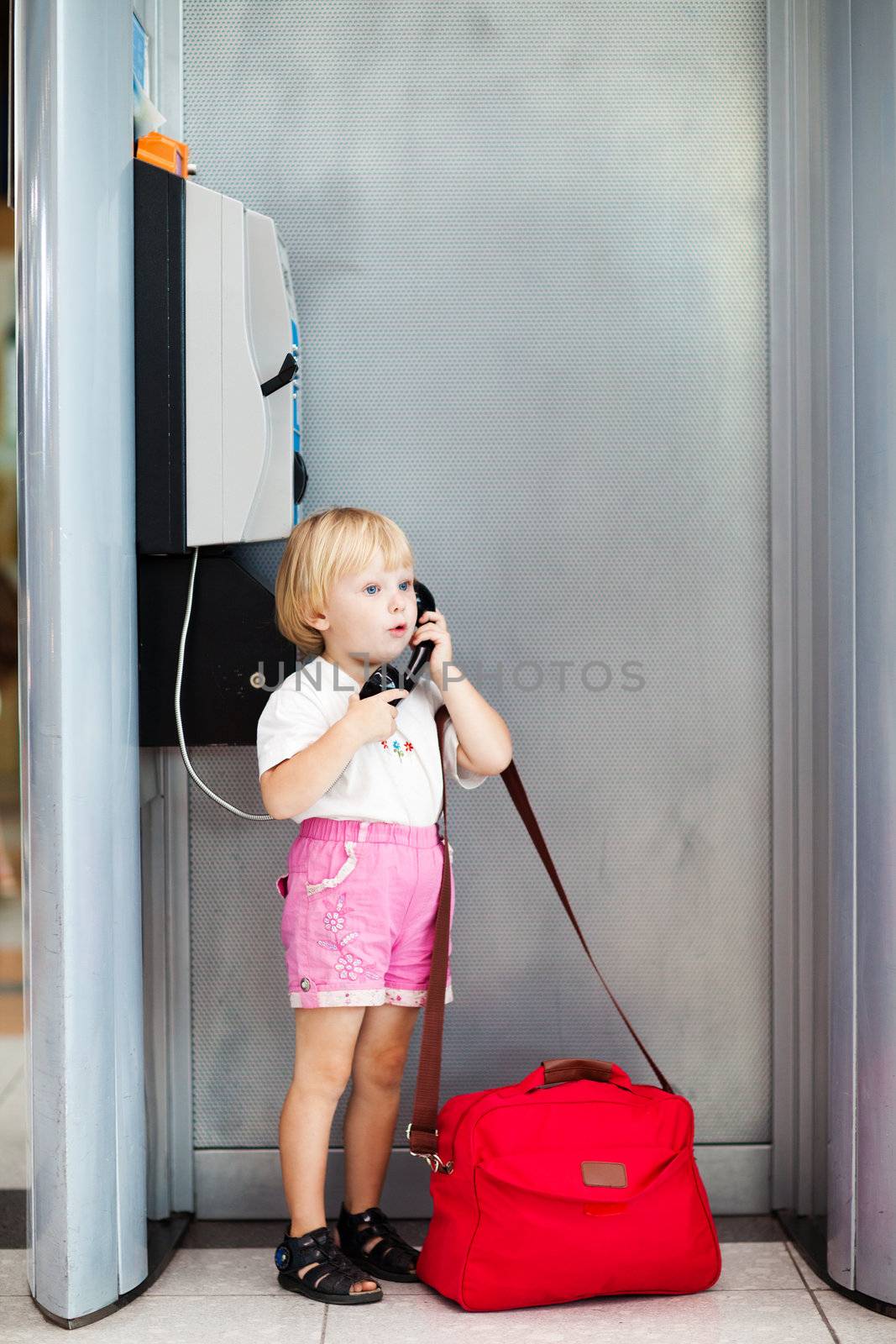 child with bag talking the phone in the airport