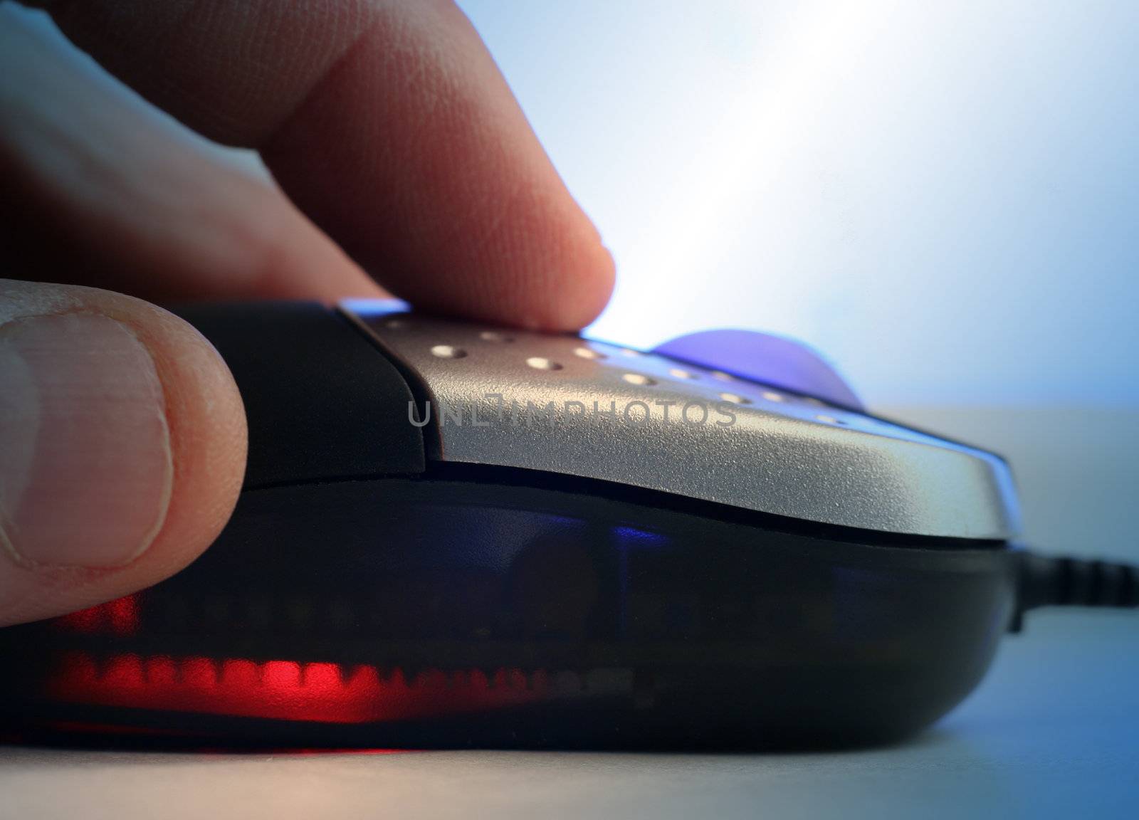 Extreme close-up of man holding computer mouse. Blue lighting effect applied.