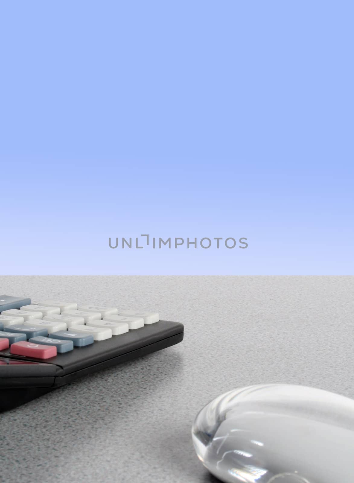 Computer mouse and office calculator on grey desk top with graduated blue background.