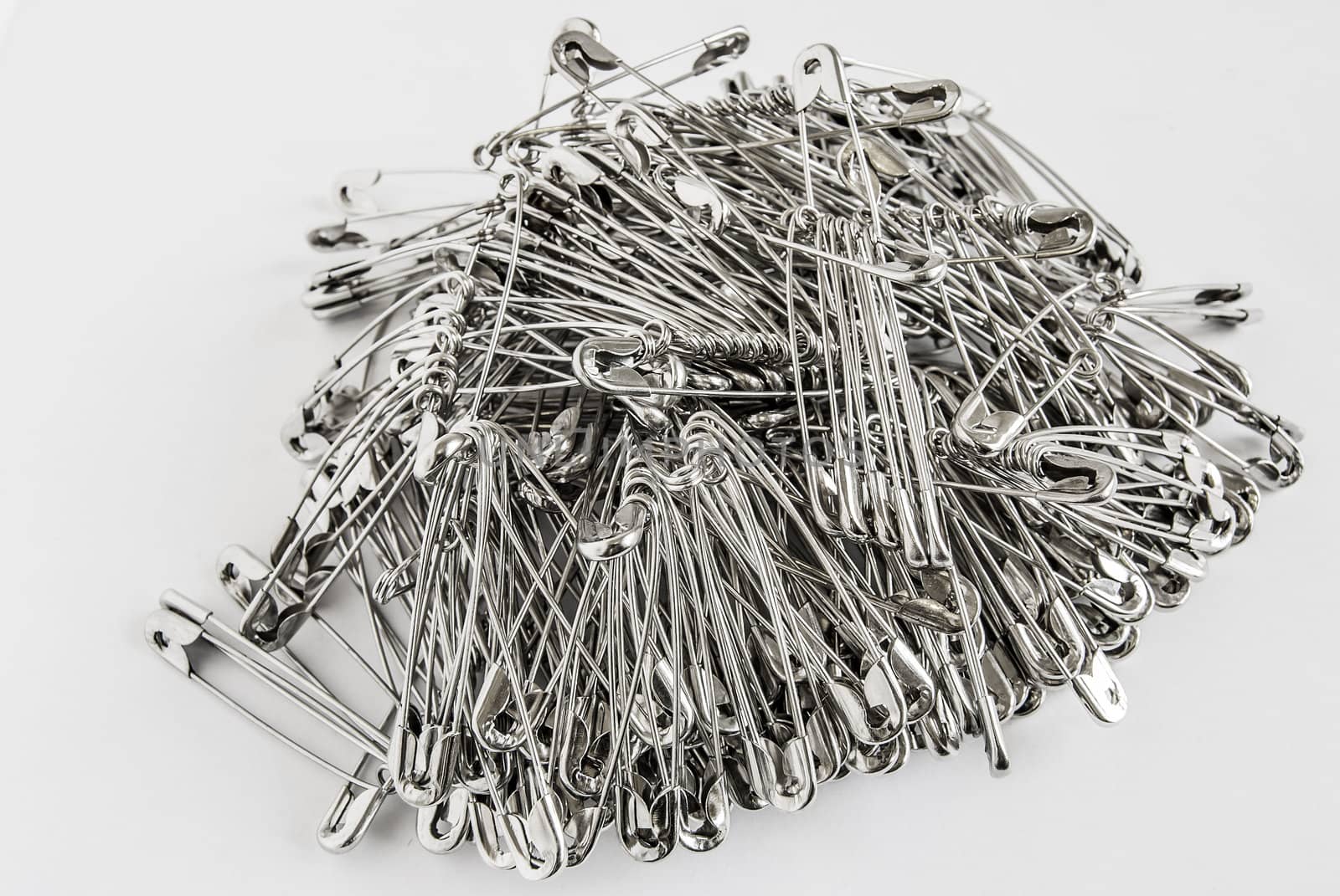 Silver colored big safety pins pile closeup