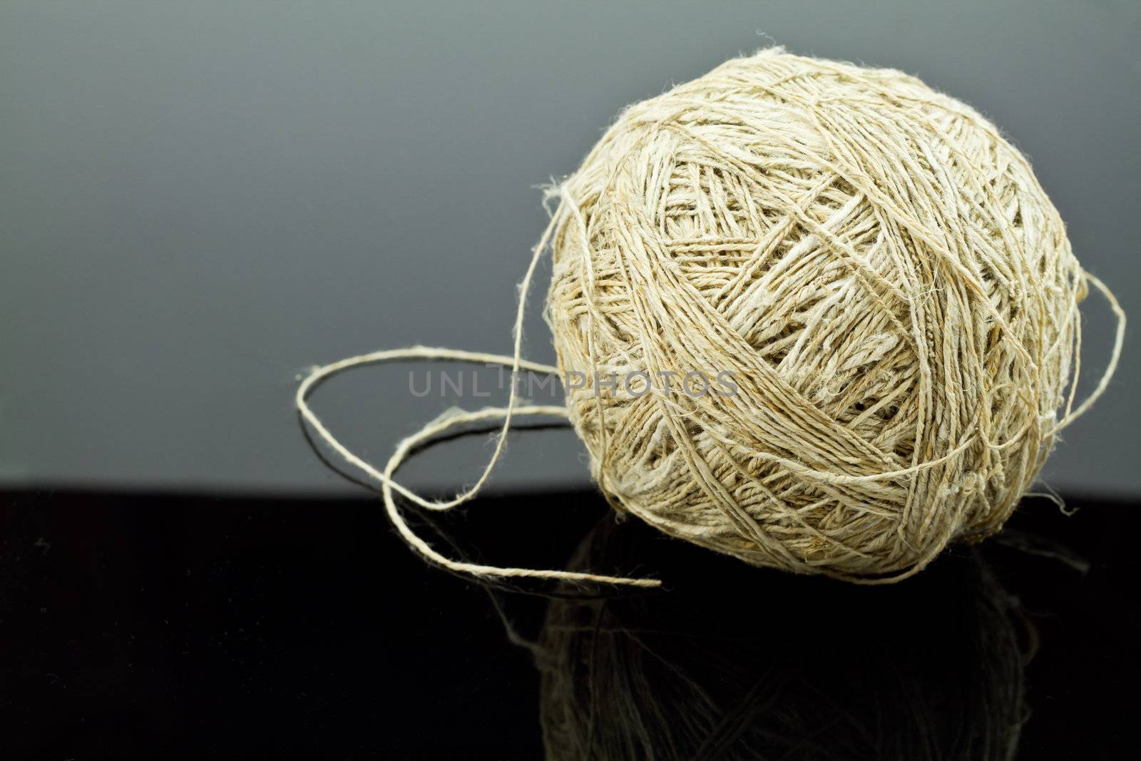 A ball of twine sits on a reflective black surface.