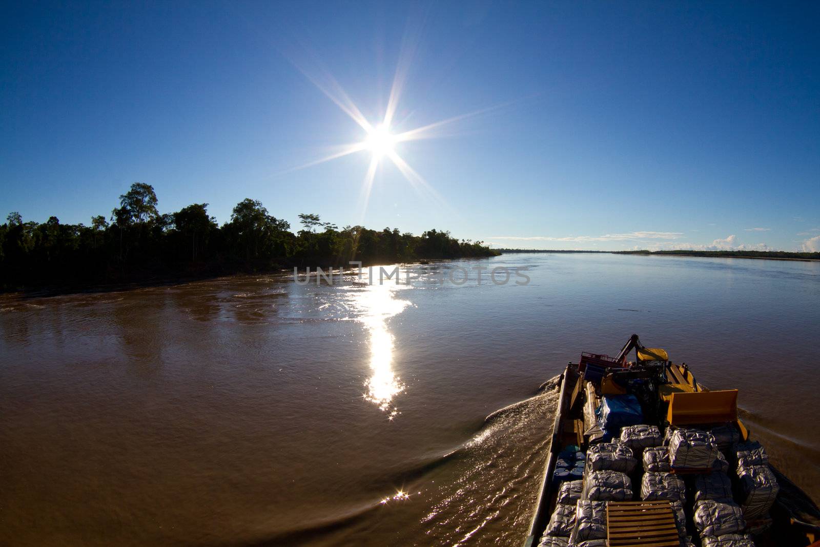 A large cargo ship moves slowly up the river Amazon to unload its cargo.