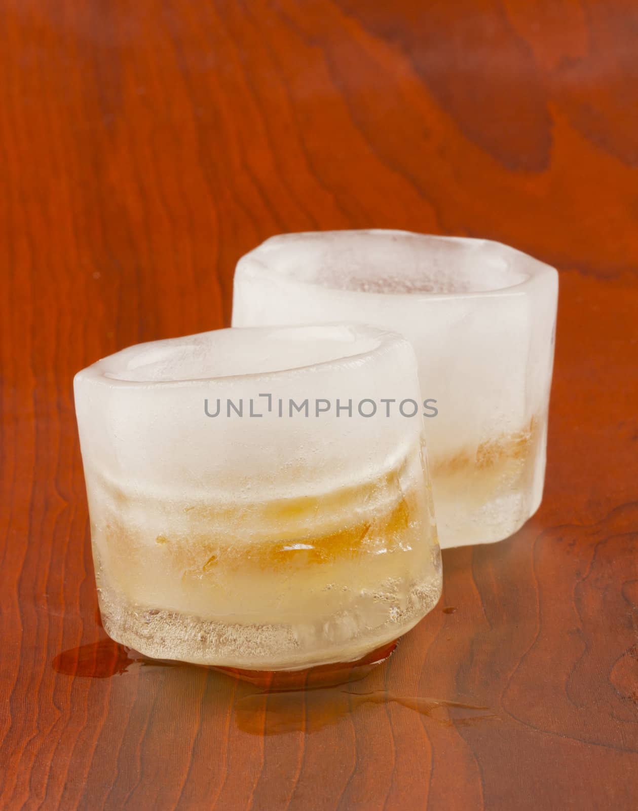 Two ice glasses full of liquor over wooden background