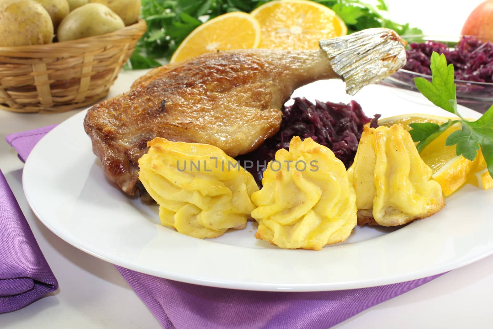 fresh delicious Duck drumstick with duchess potatoes and red cabbage on a light background