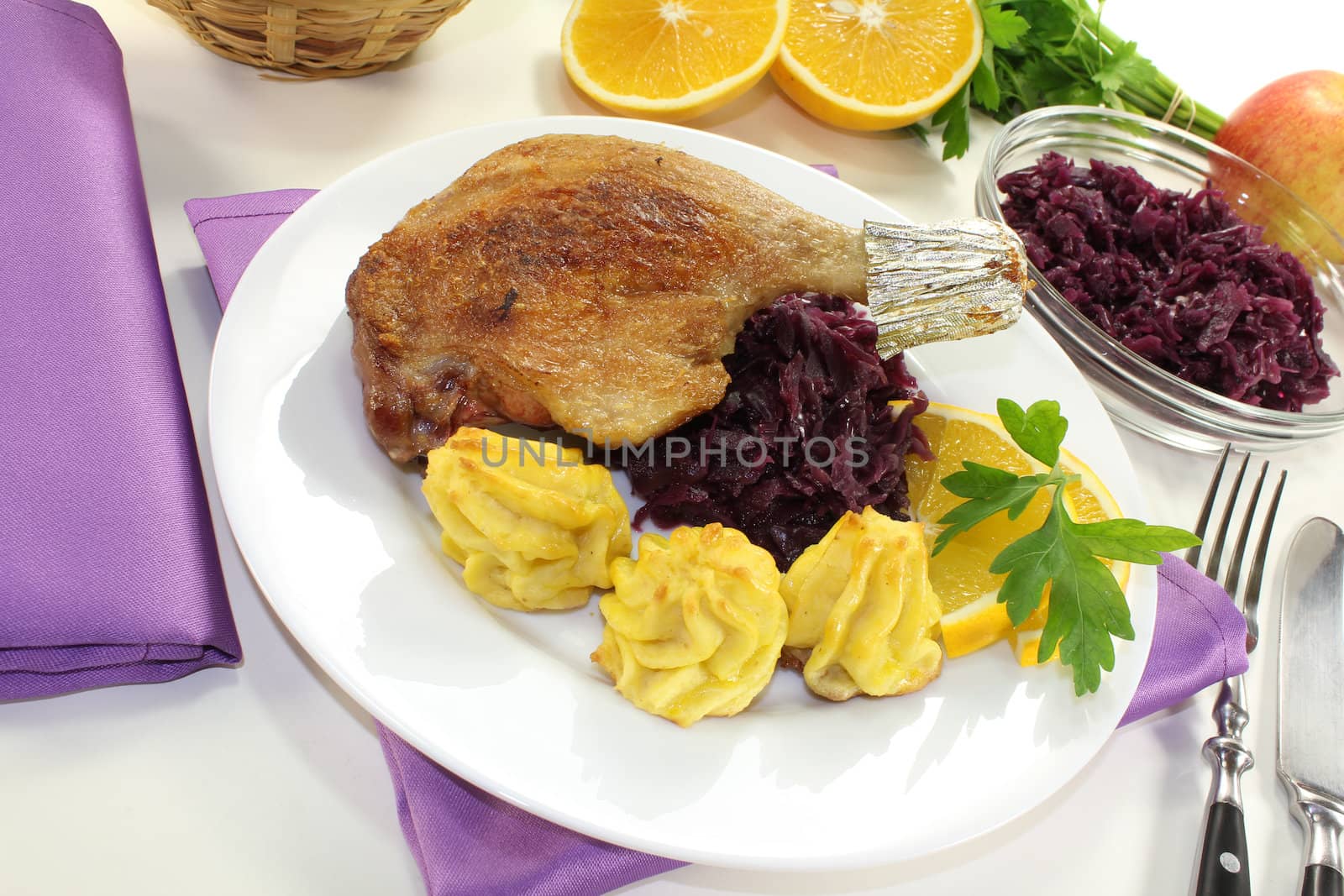 fresh Duck drumstick with duchess potatoes and red cabbage on a light background