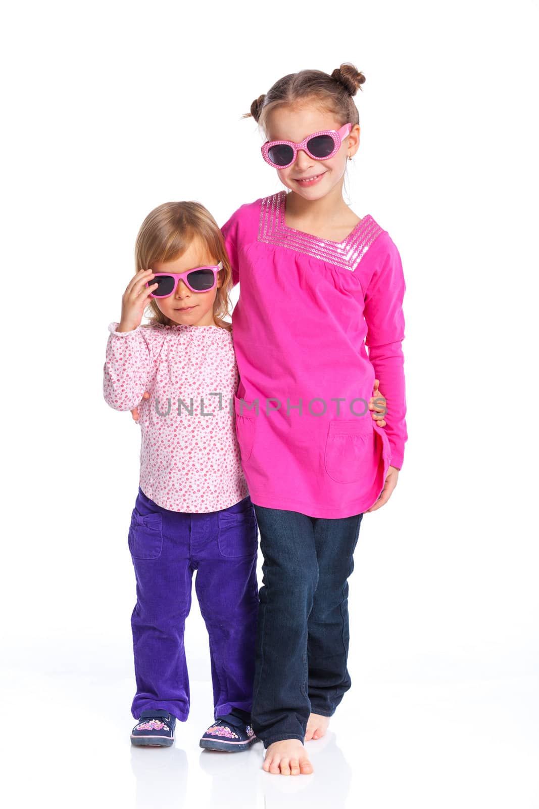 Two happy adorable smiling sisters in sunglasses. Isolated white background