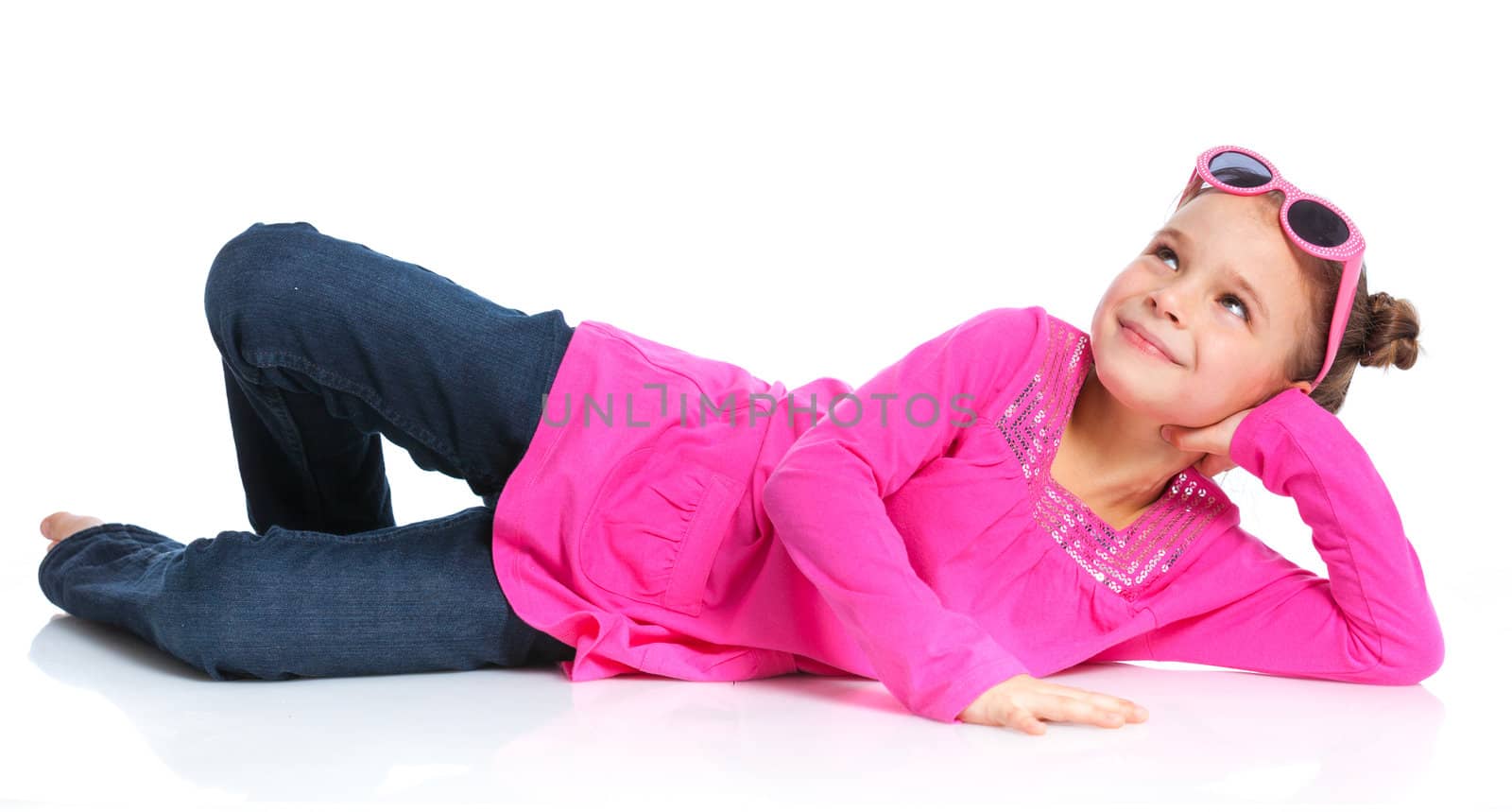 Little fashion girl lying in pink dress and sunglasses. Isolated white backround.