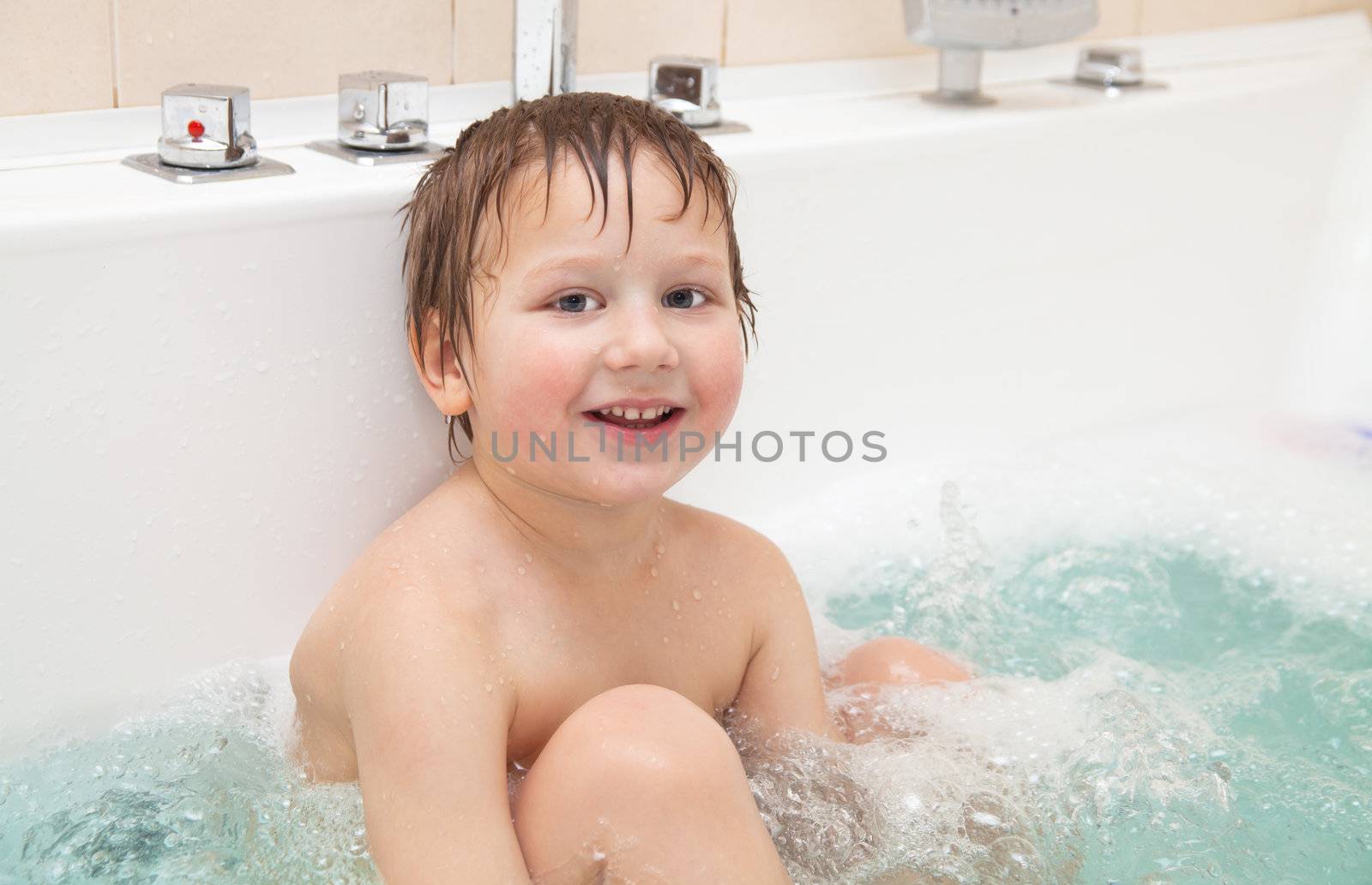 Happy little boy taking bath at home