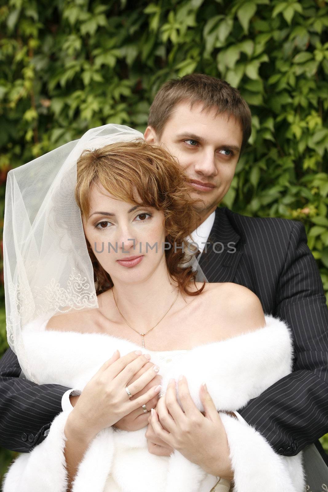 The groom embraces the bride in park