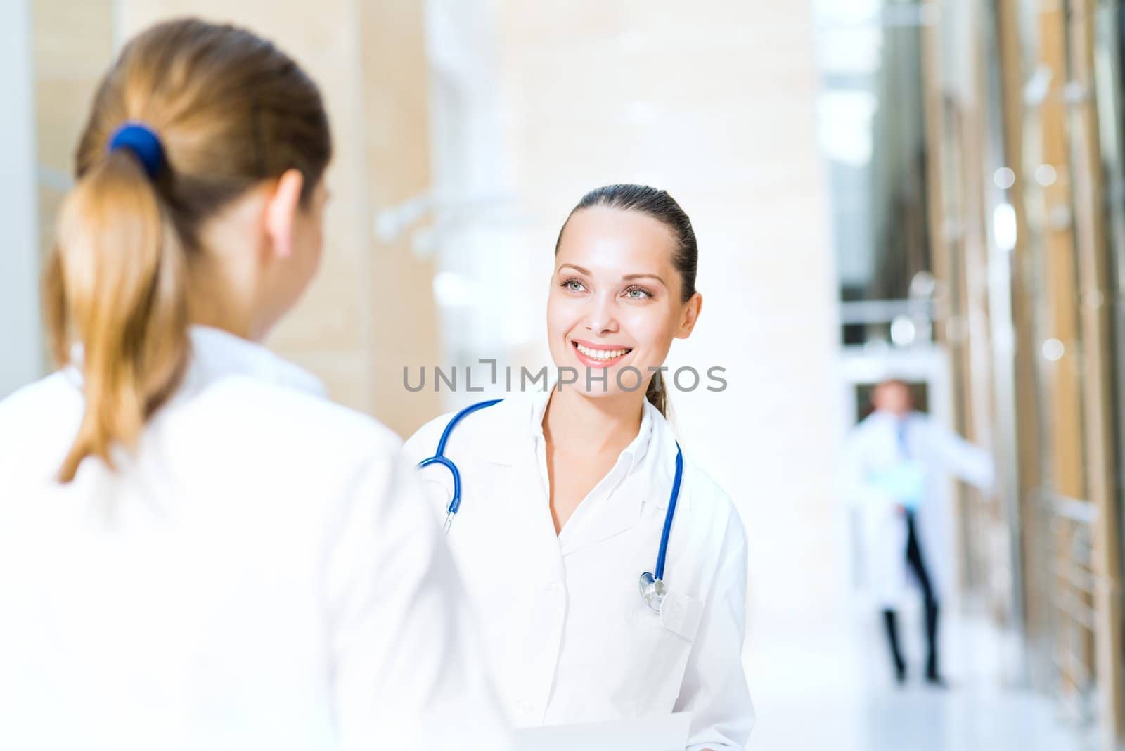 two doctors talking in the lobby of the hospital, holding the documents in the background go to other doctors