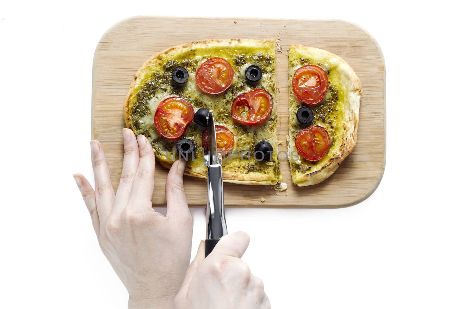 Image of human hand slicing a pizza on wooden plate on white background