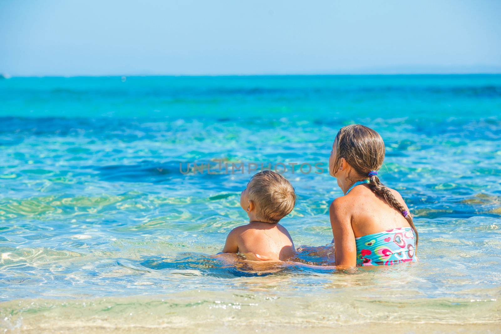 Happy kids. Sister and brother playing and swimming in the transparent sea