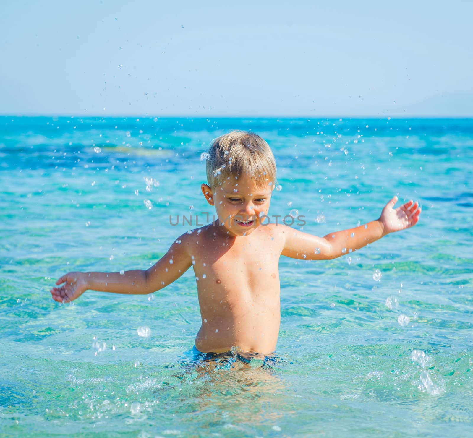 Portrait of young boy swimming and squirting in the transparent sea
